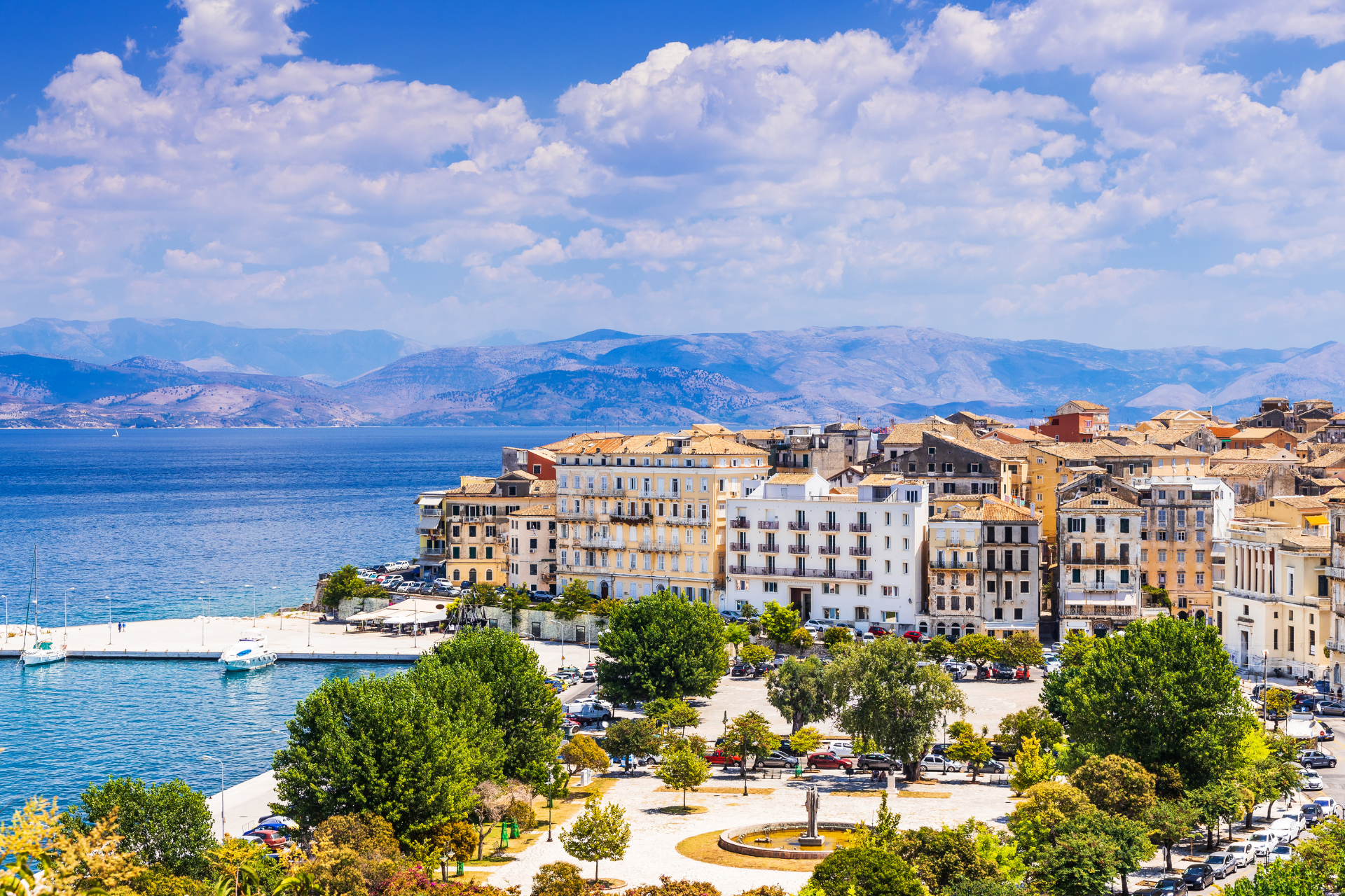 An aerial view of a city next to the ocean with mountains in the background.