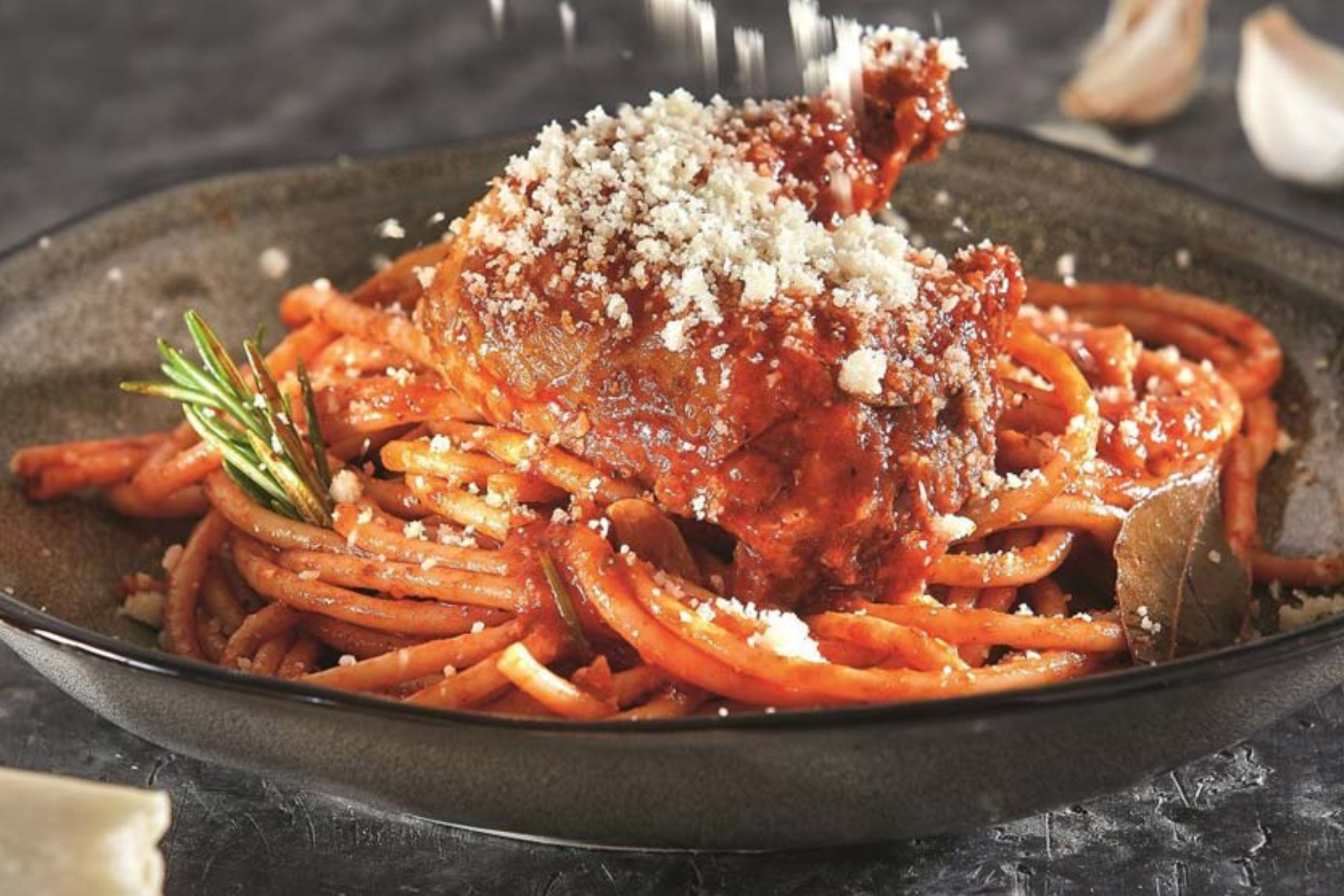 A plate of spaghetti with meat and cheese on top