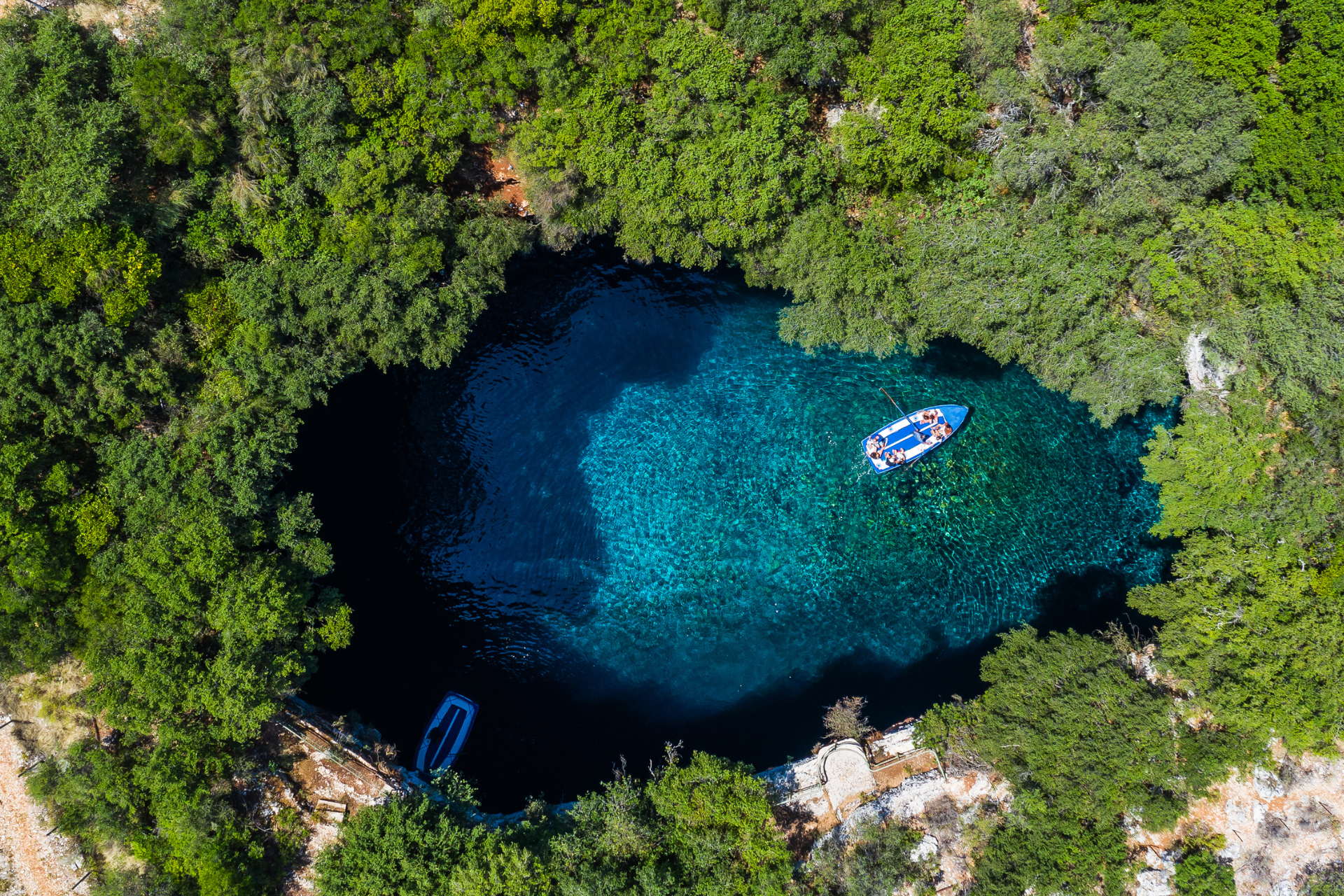 An aerial view of a lake surrounded by trees with a boat in it.