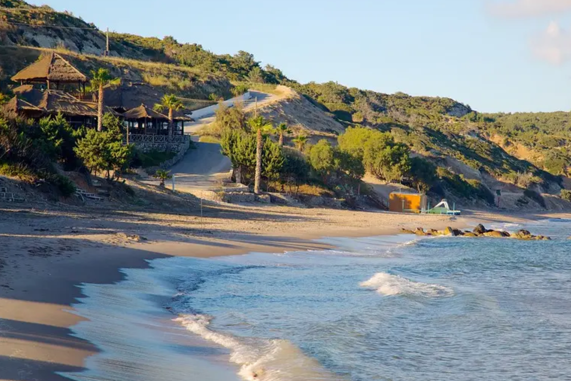 A beach with a house on the hill in the background