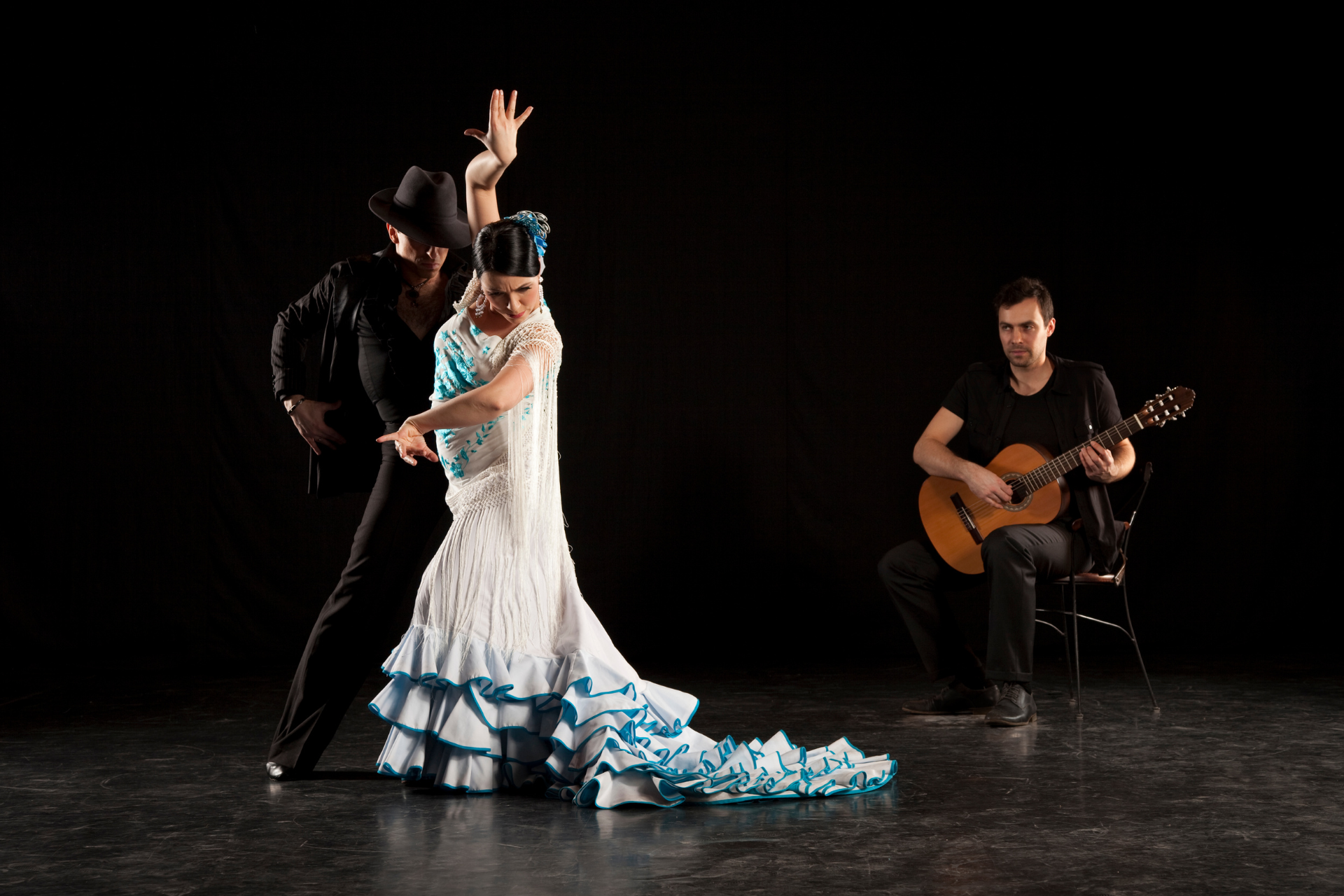 A man is playing a guitar while a woman is dancing flamenco.