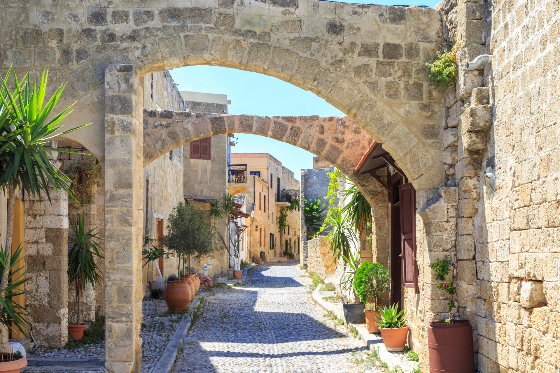 A stone archway leading to a narrow alleyway between two buildings.