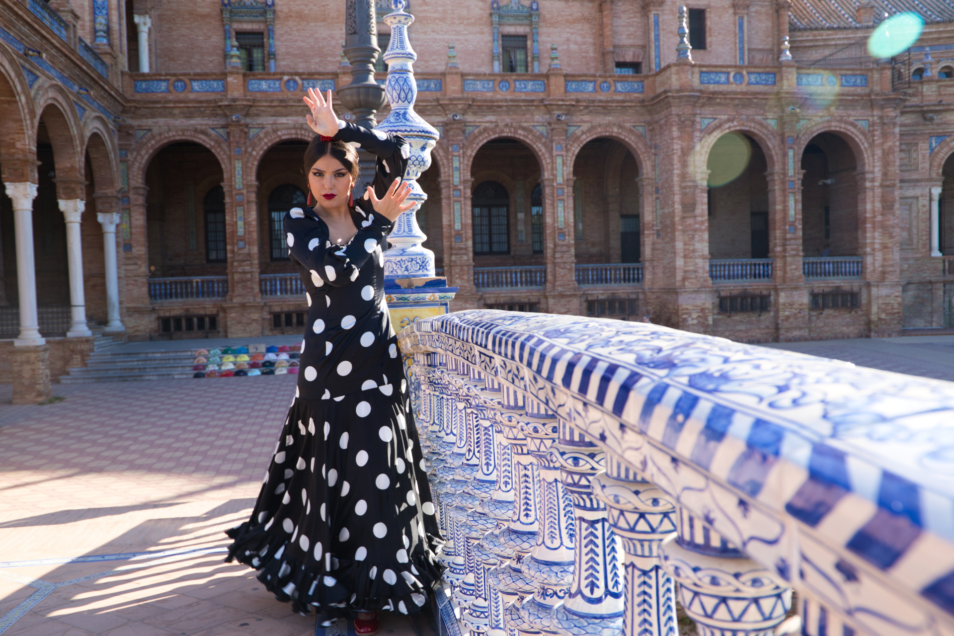 A woman in a polka dot dress is standing next to a blue and white tiled wall.