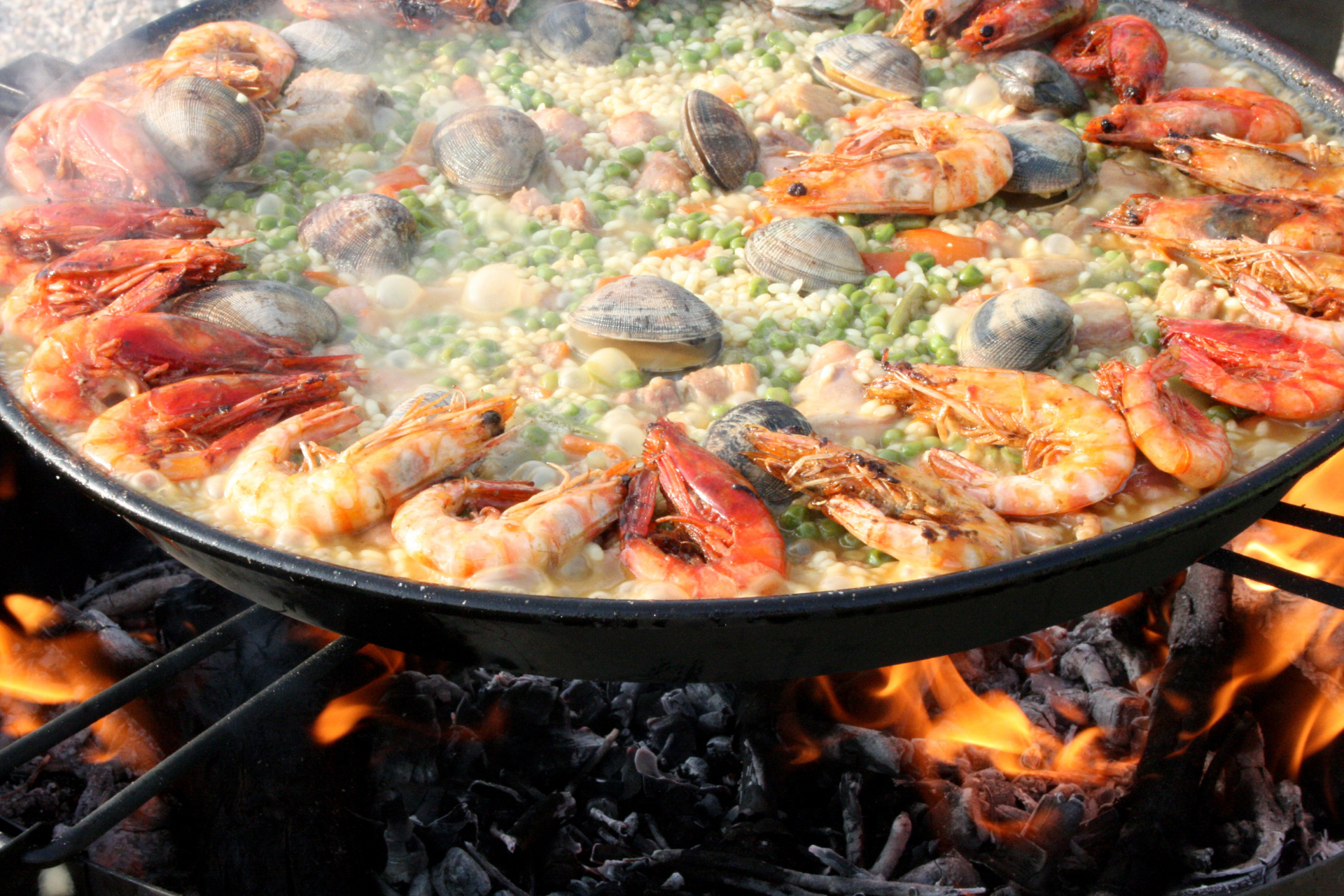 A paella is being cooked on a grill over a fire.