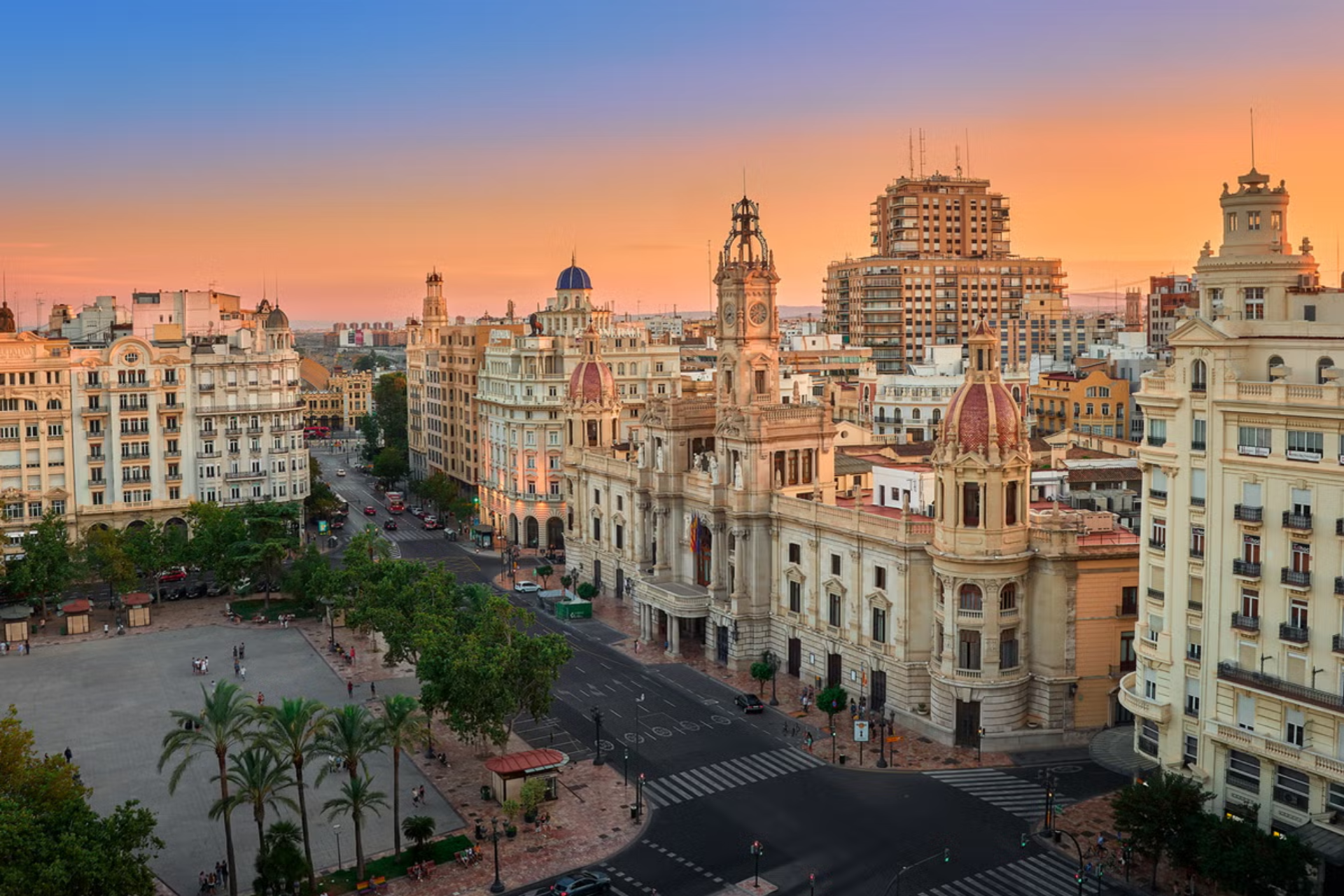 An aerial view of a city at sunset with lots of buildings and trees.