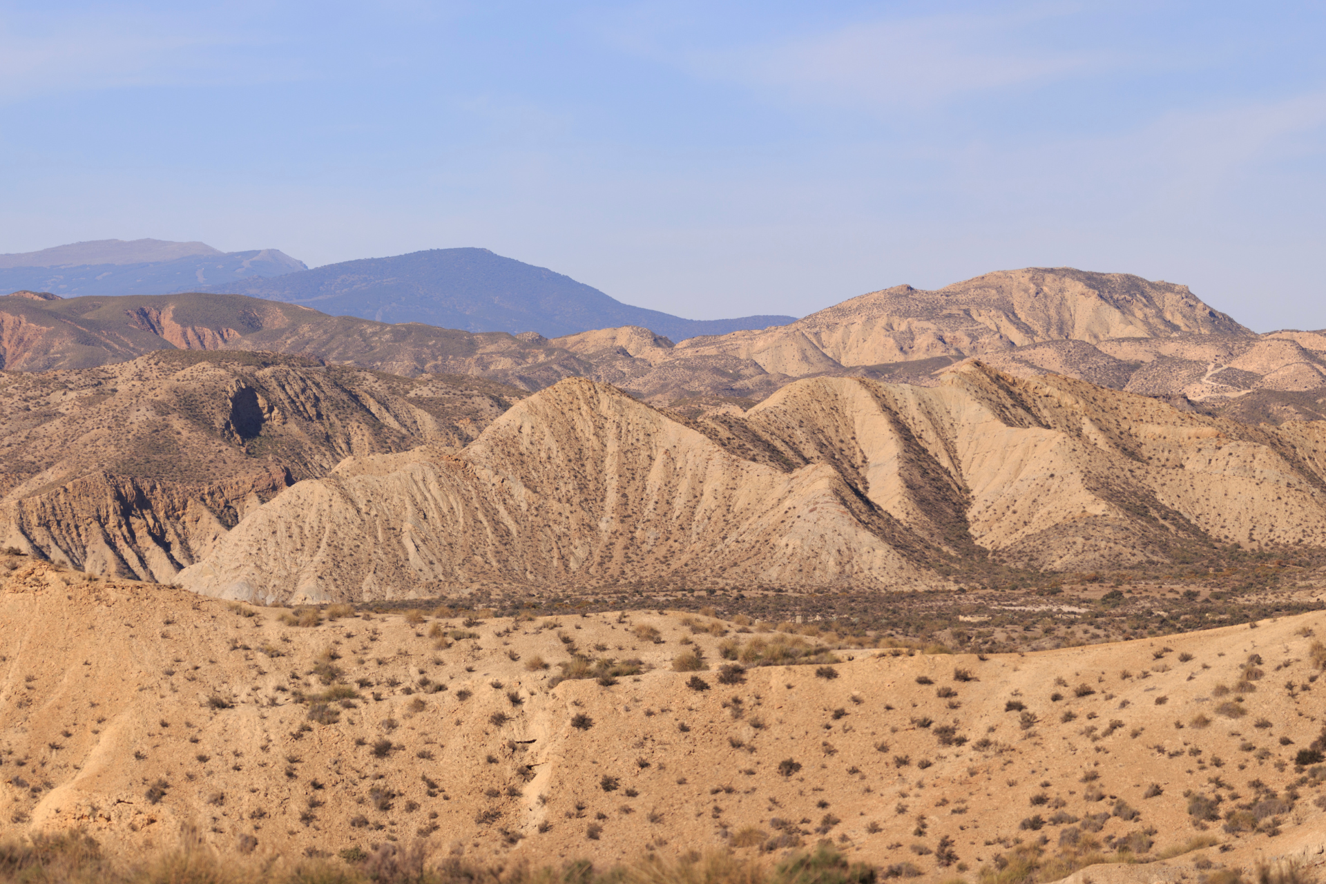 A desert landscape with mountains in the background and a blue sky