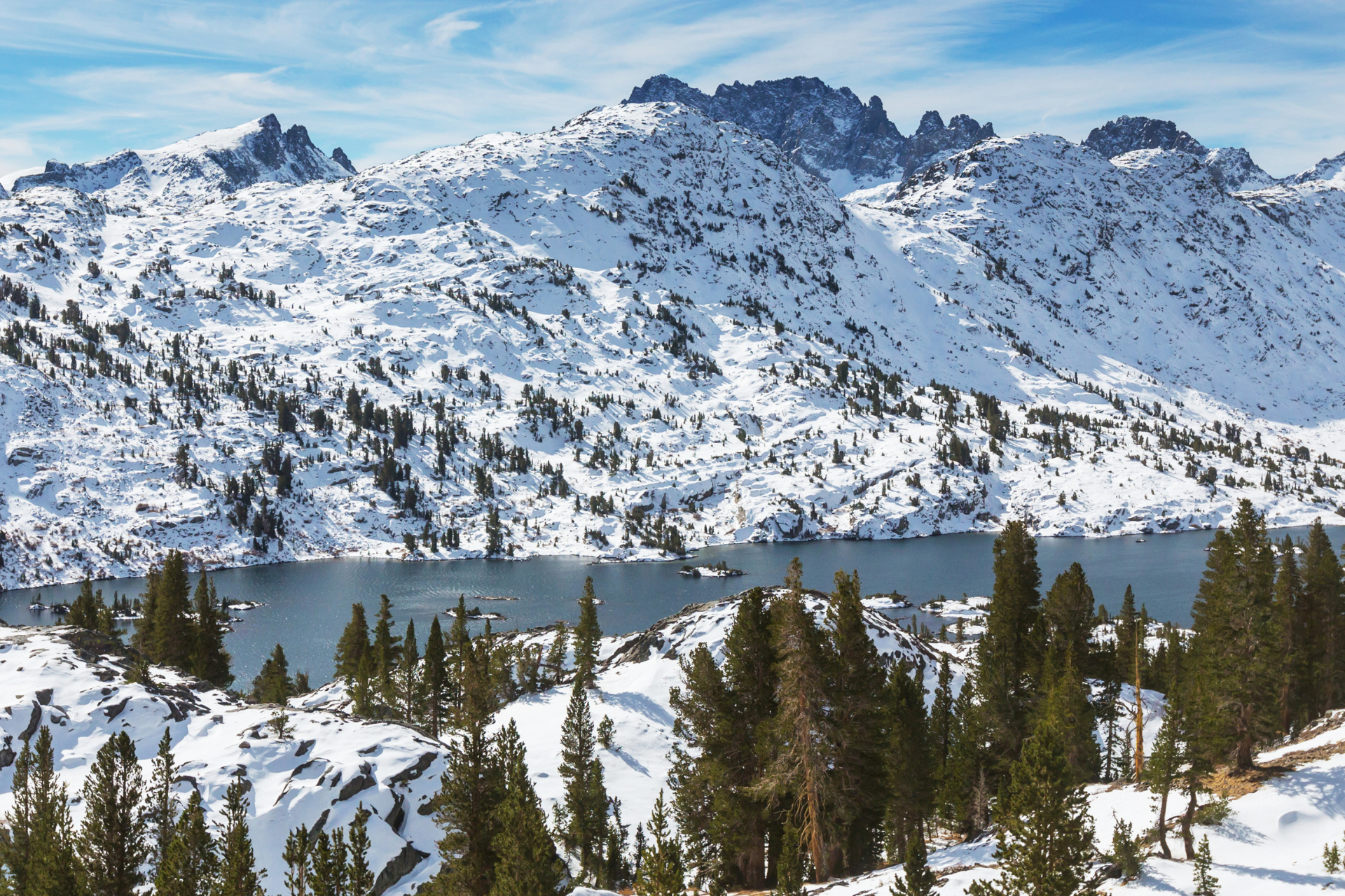 A lake surrounded by snow covered mountains and trees