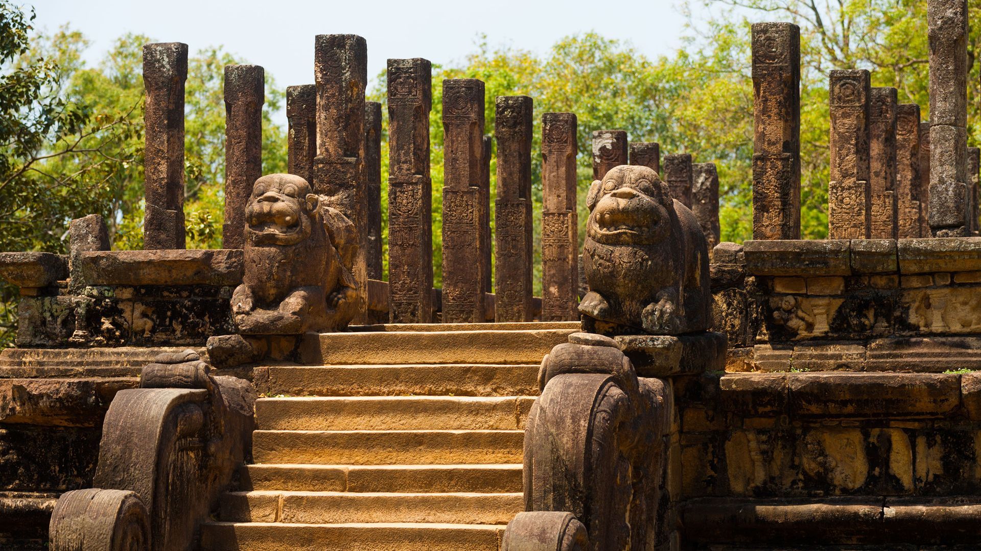 A stone statue of a lion is sitting on top of a set of stairs.