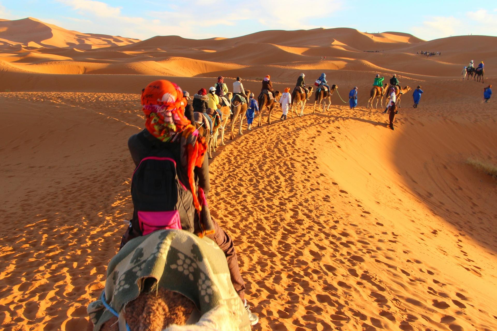 A group of people are riding camels in the desert.