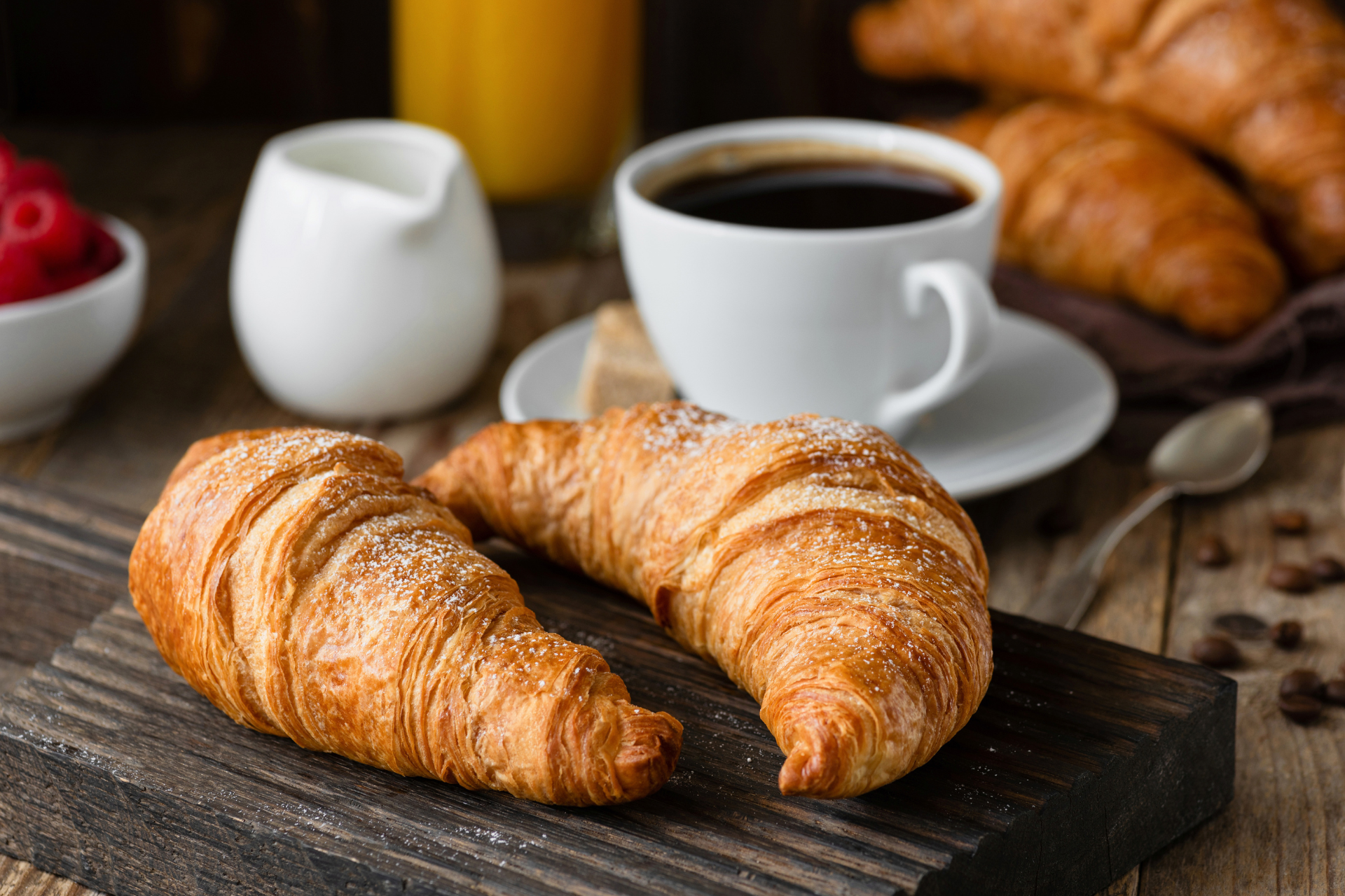 Two croissants and a cup of coffee on a wooden table.