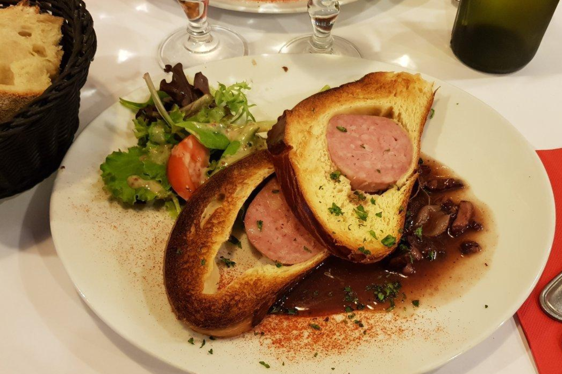 A white plate topped with meat and bread on a table.