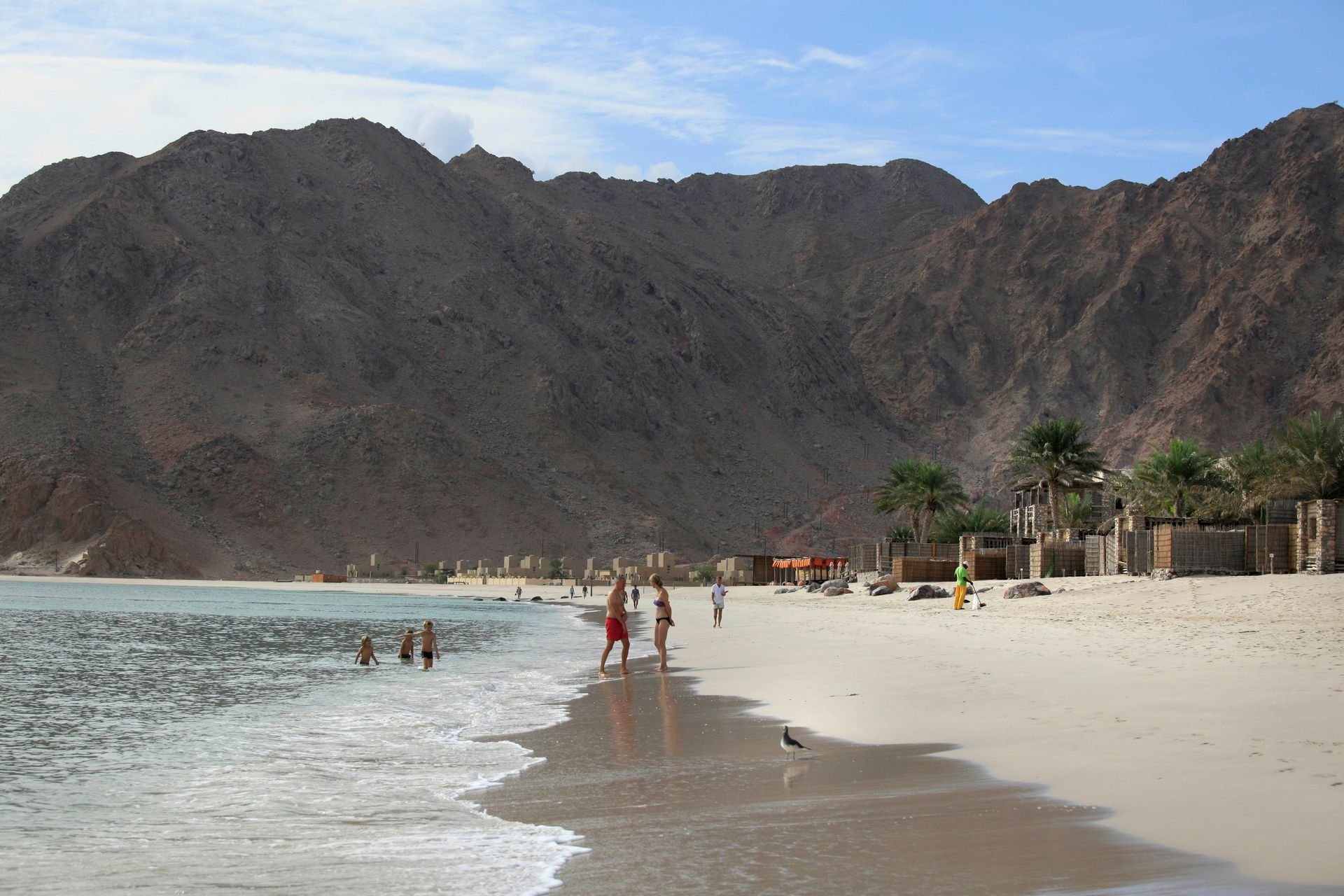 People walking on a beach with mountains in the background