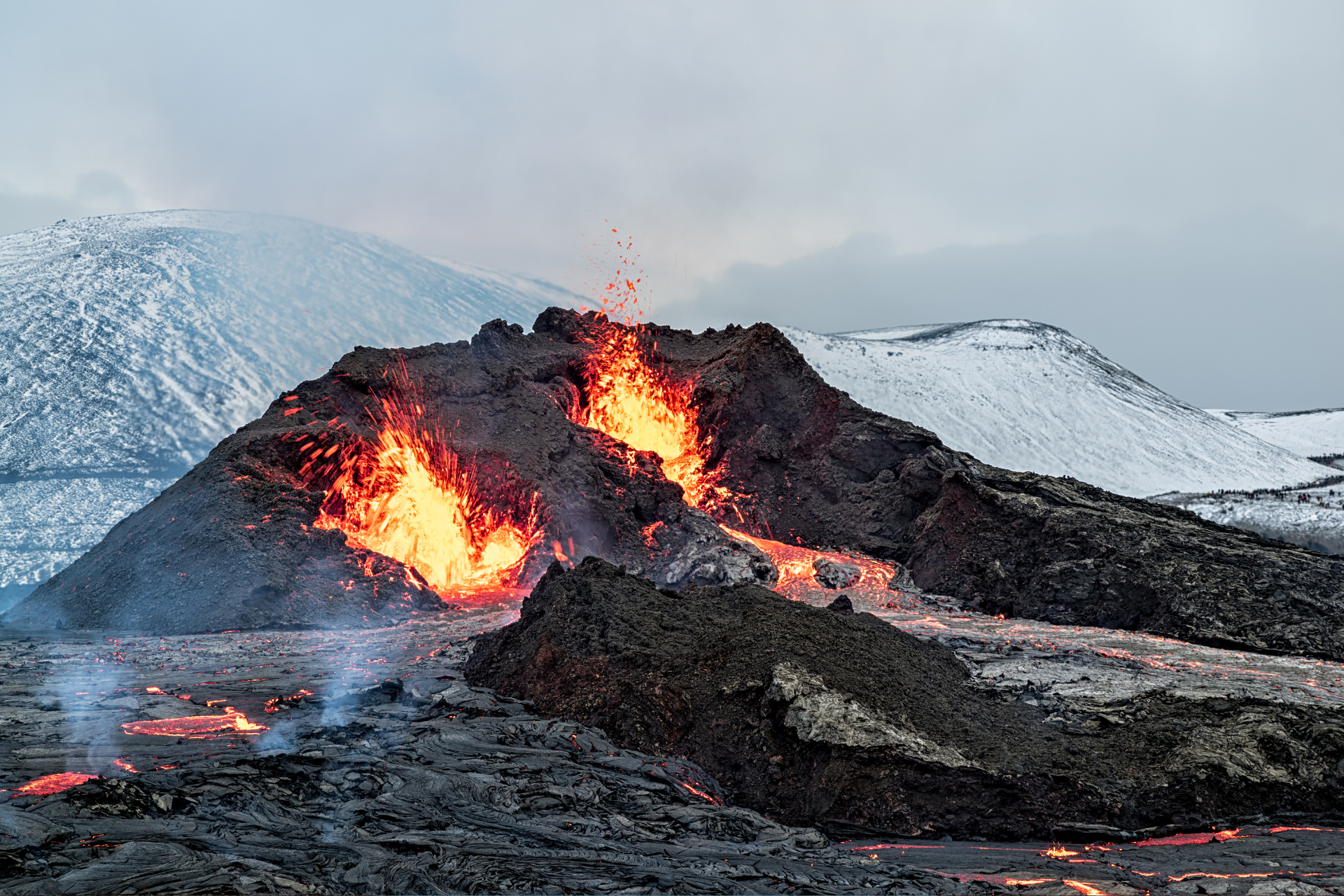 A volcano is erupting in the middle of a snowy field.