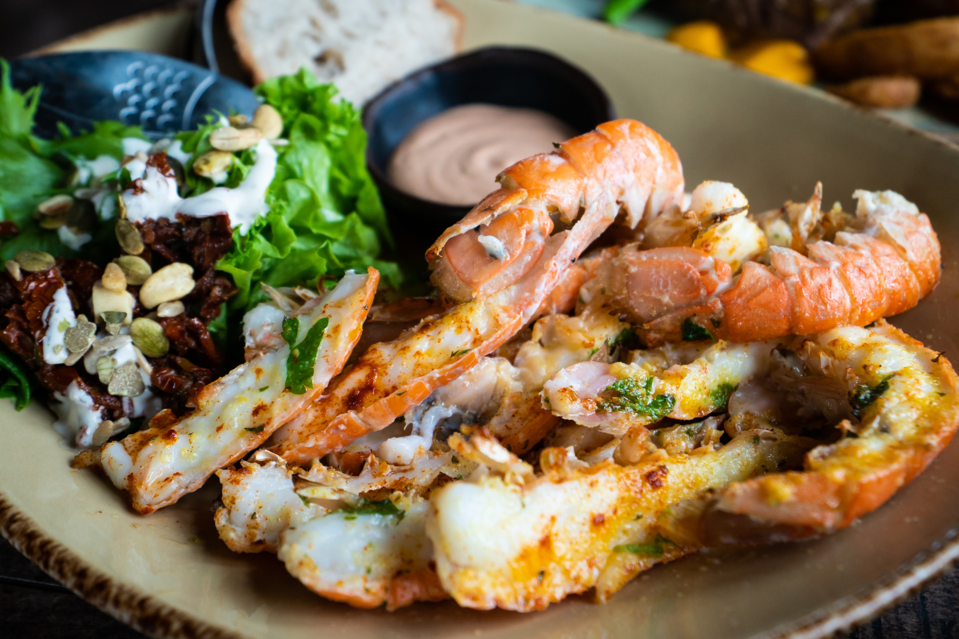 A close up of a plate of food with shrimp and salad on a table.