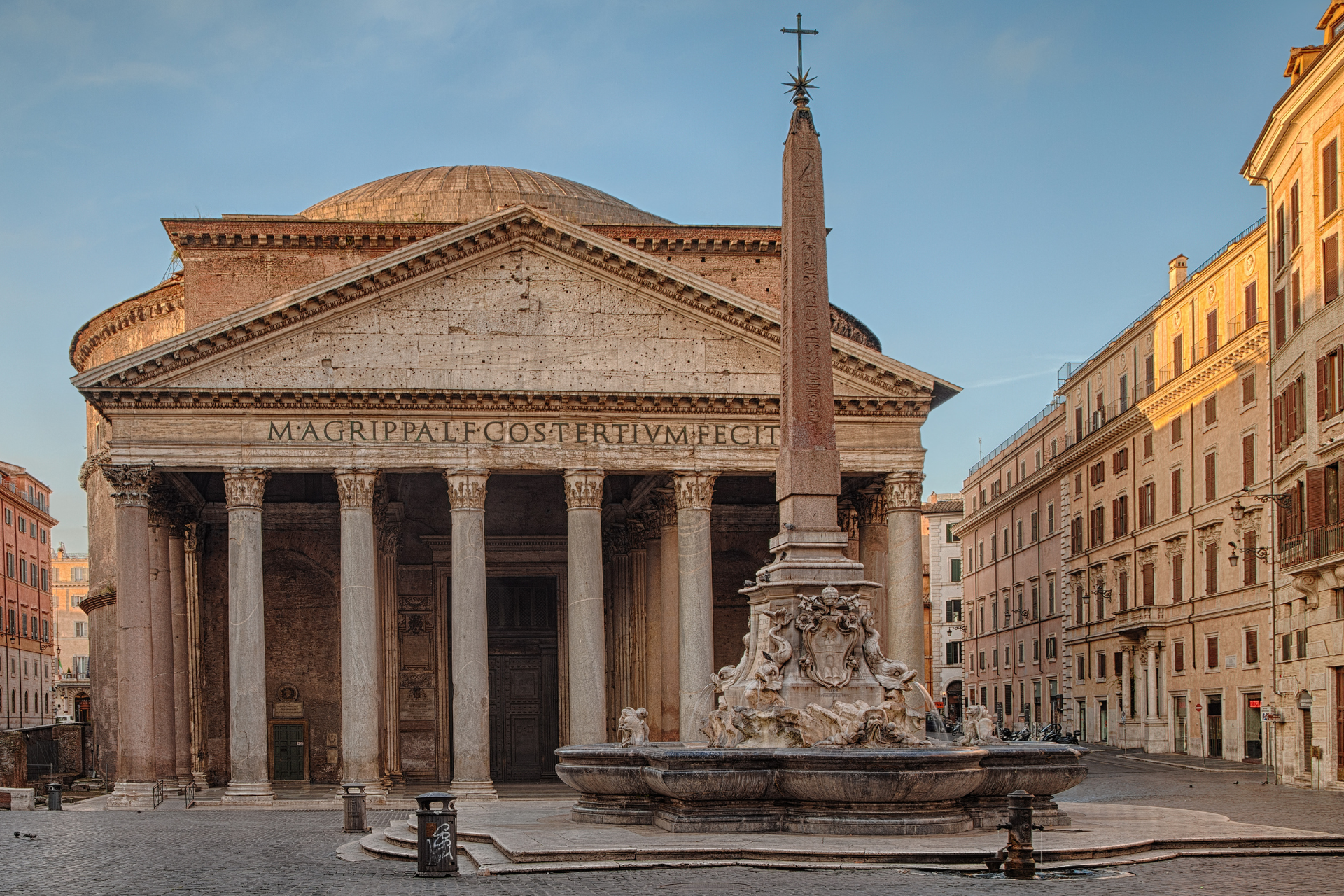 A large building with columns and a fountain in front of it.