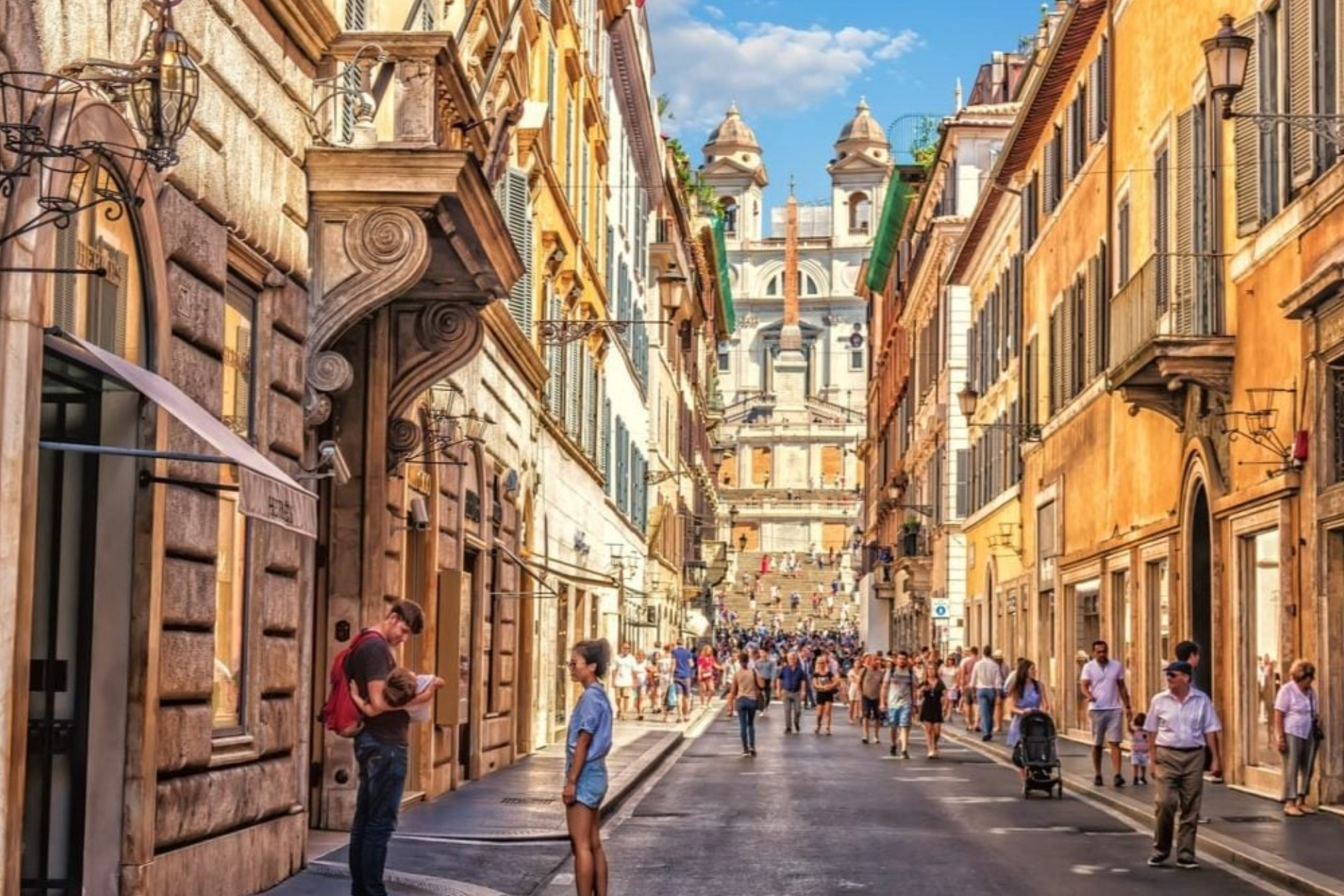 A group of people are walking down a narrow street in a city.