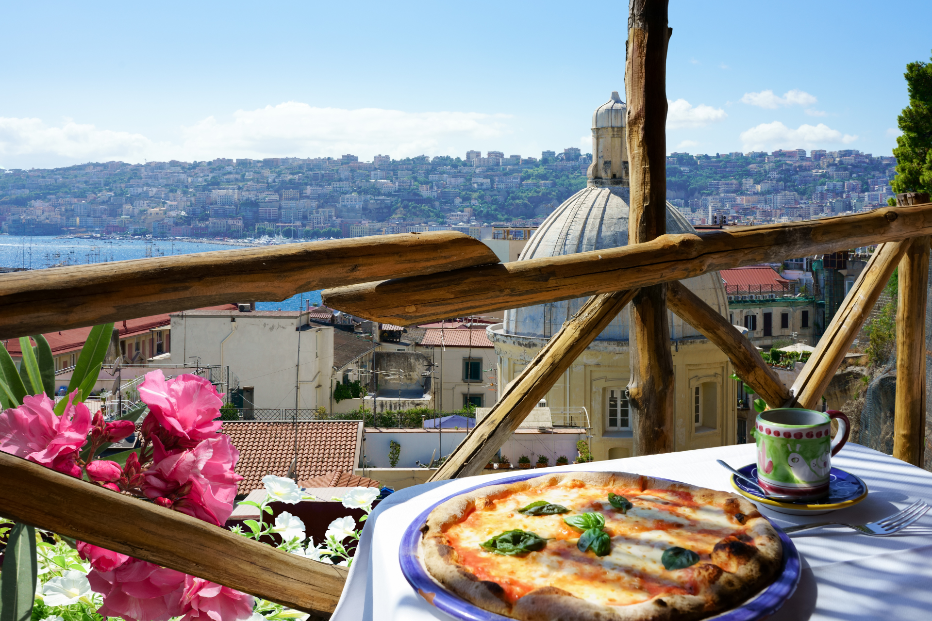 A pizza and a cup of coffee on a table with a view of a city.