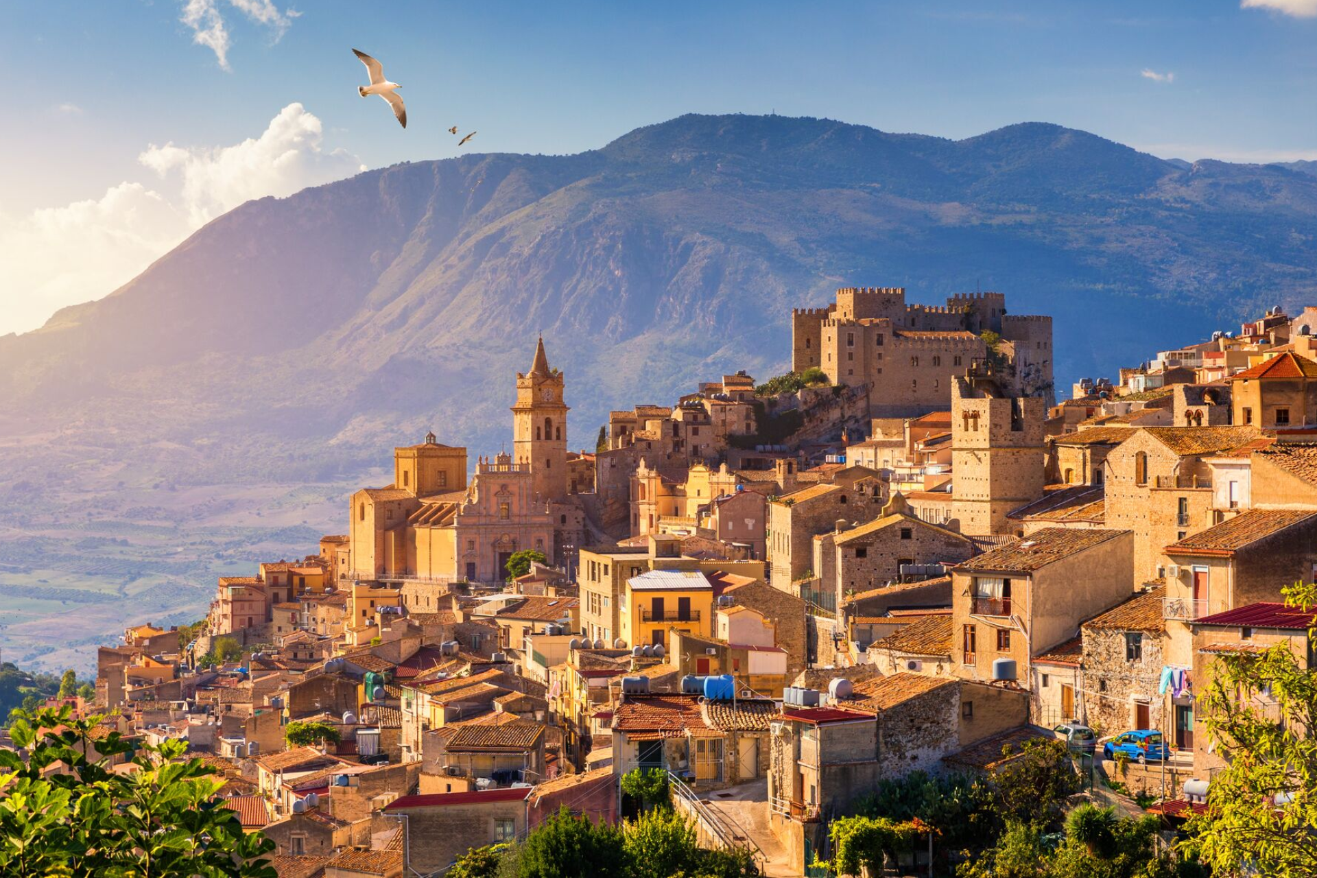 A small town on a hill with mountains in the background.