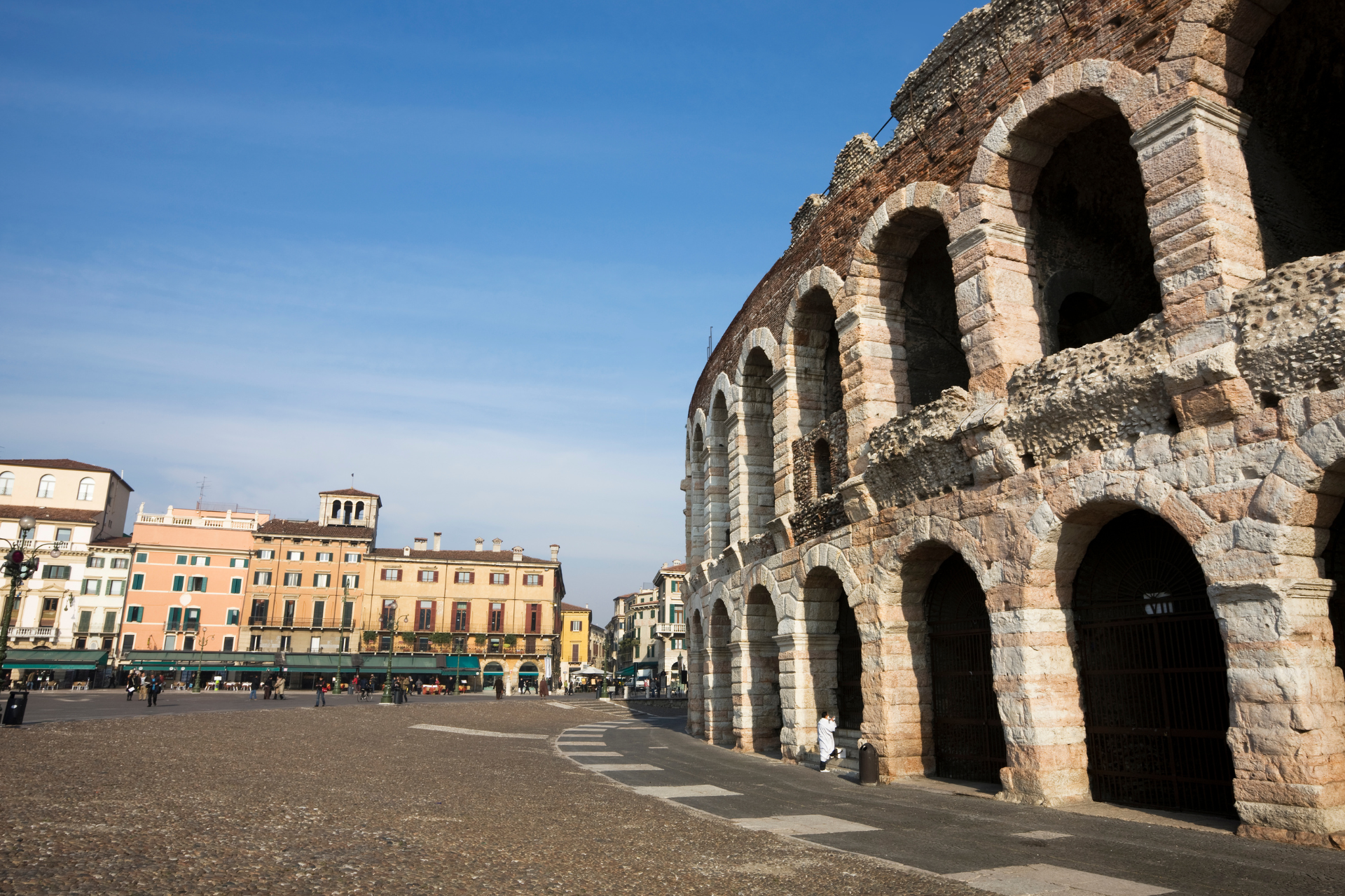 A large stone building with arches and a blue sky in the background