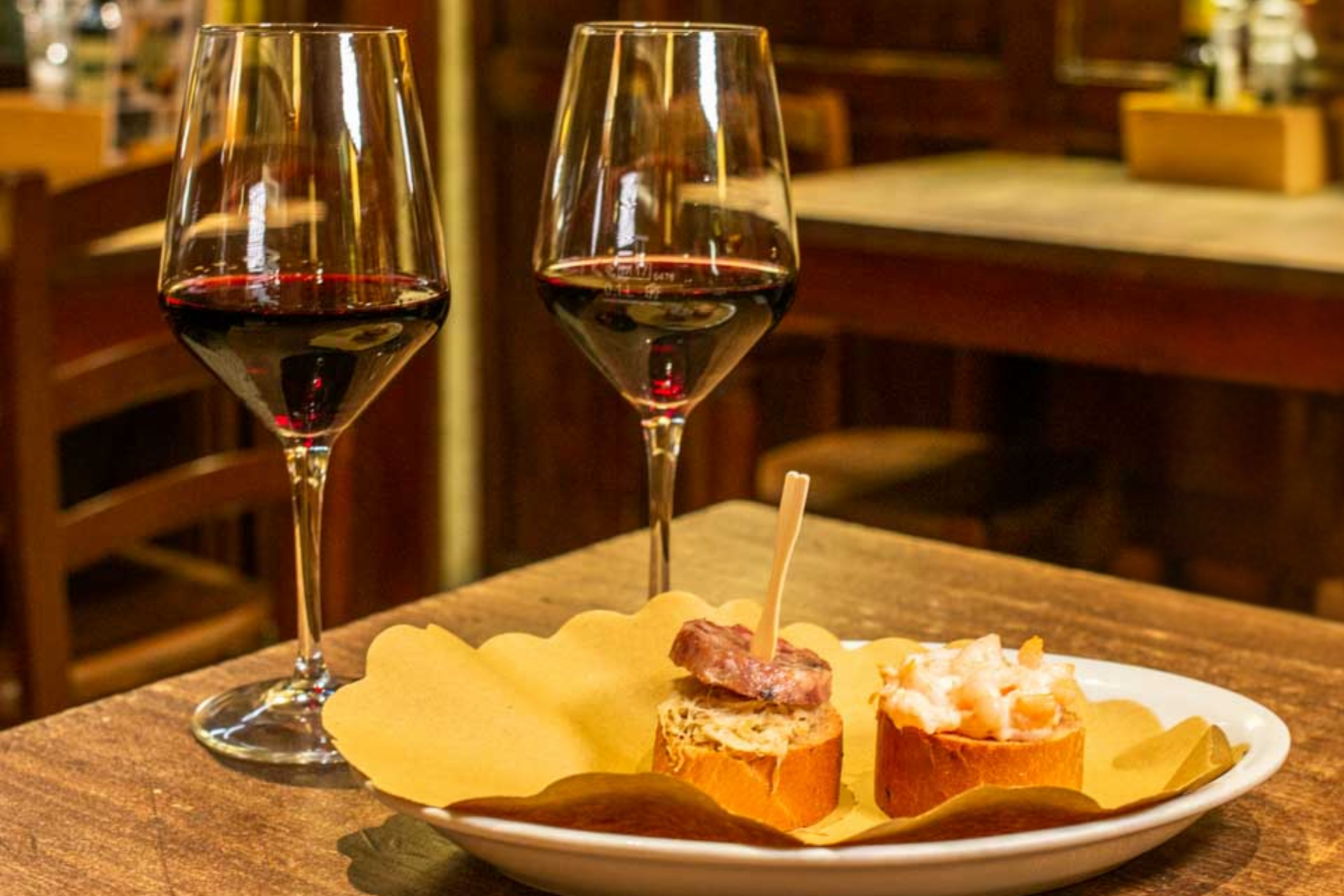 Two glasses of wine and a plate of food on a table.