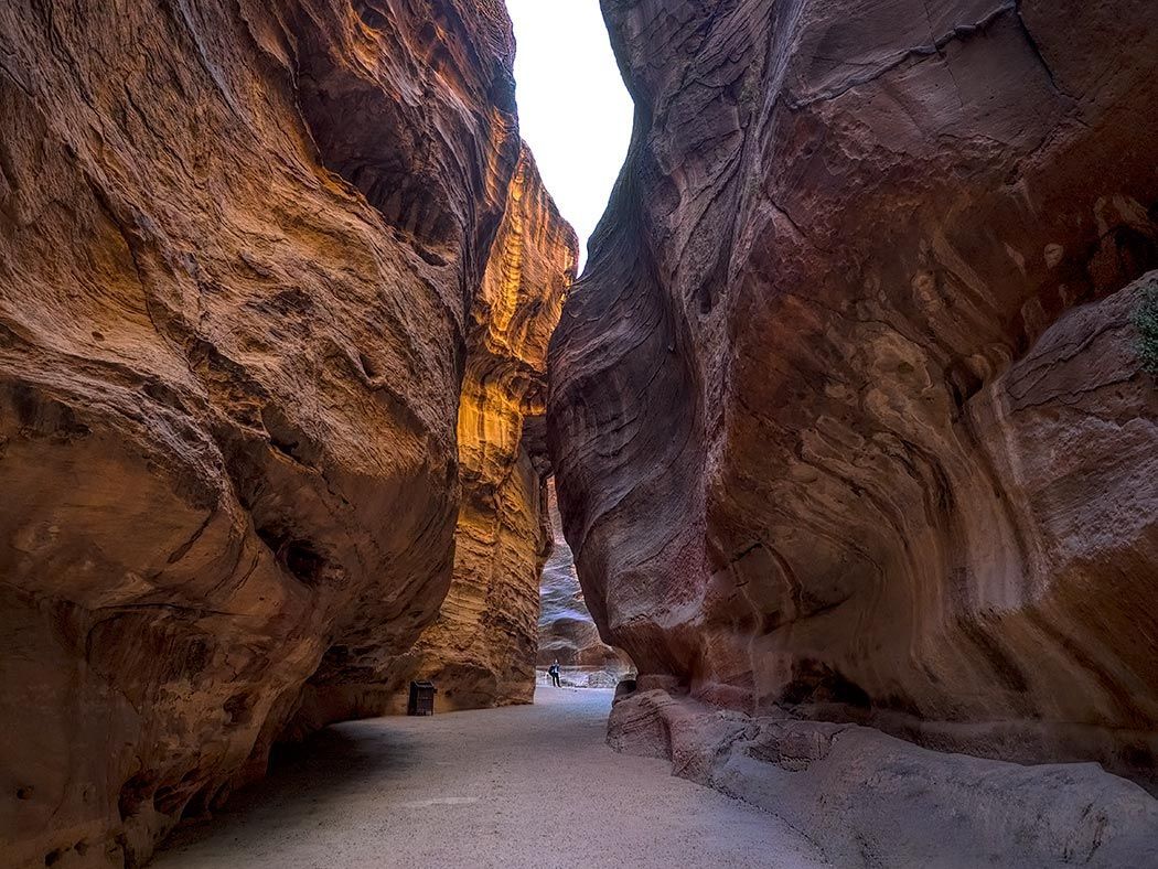 A person is walking through a canyon between two large rocks.