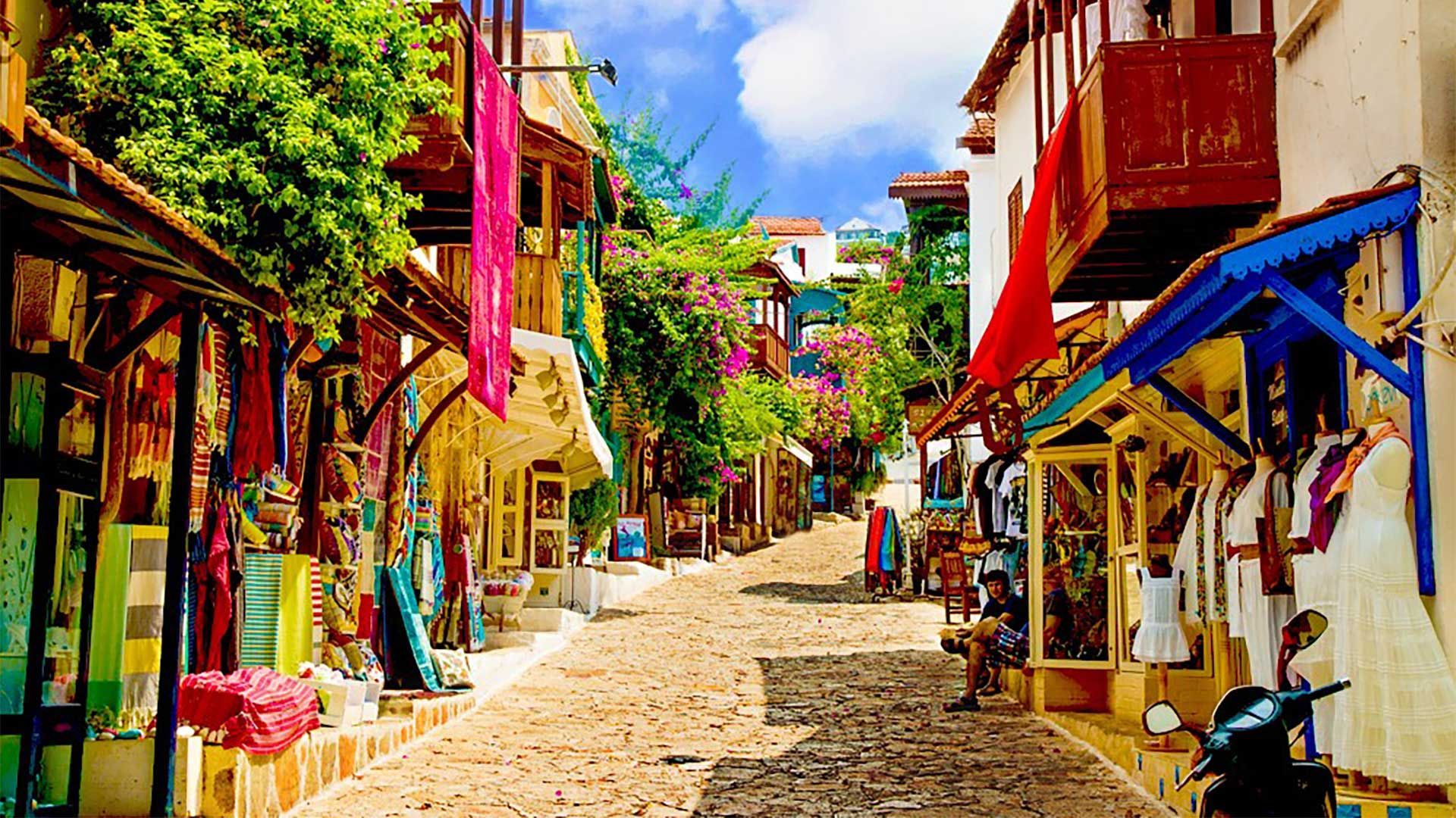 A narrow cobblestone street lined with shops and a motorcycle.