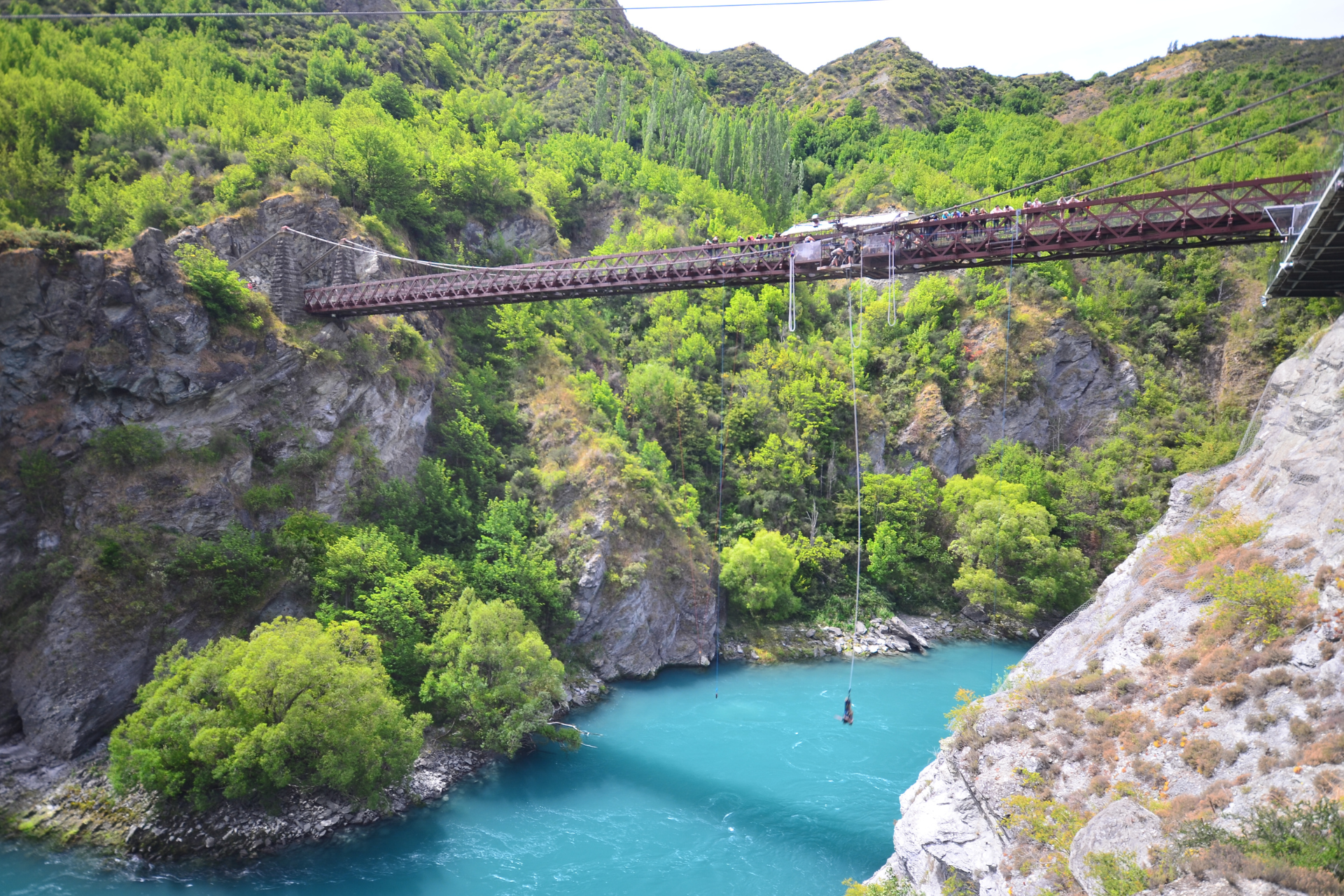 A person is jumping off a bridge into a body of water.