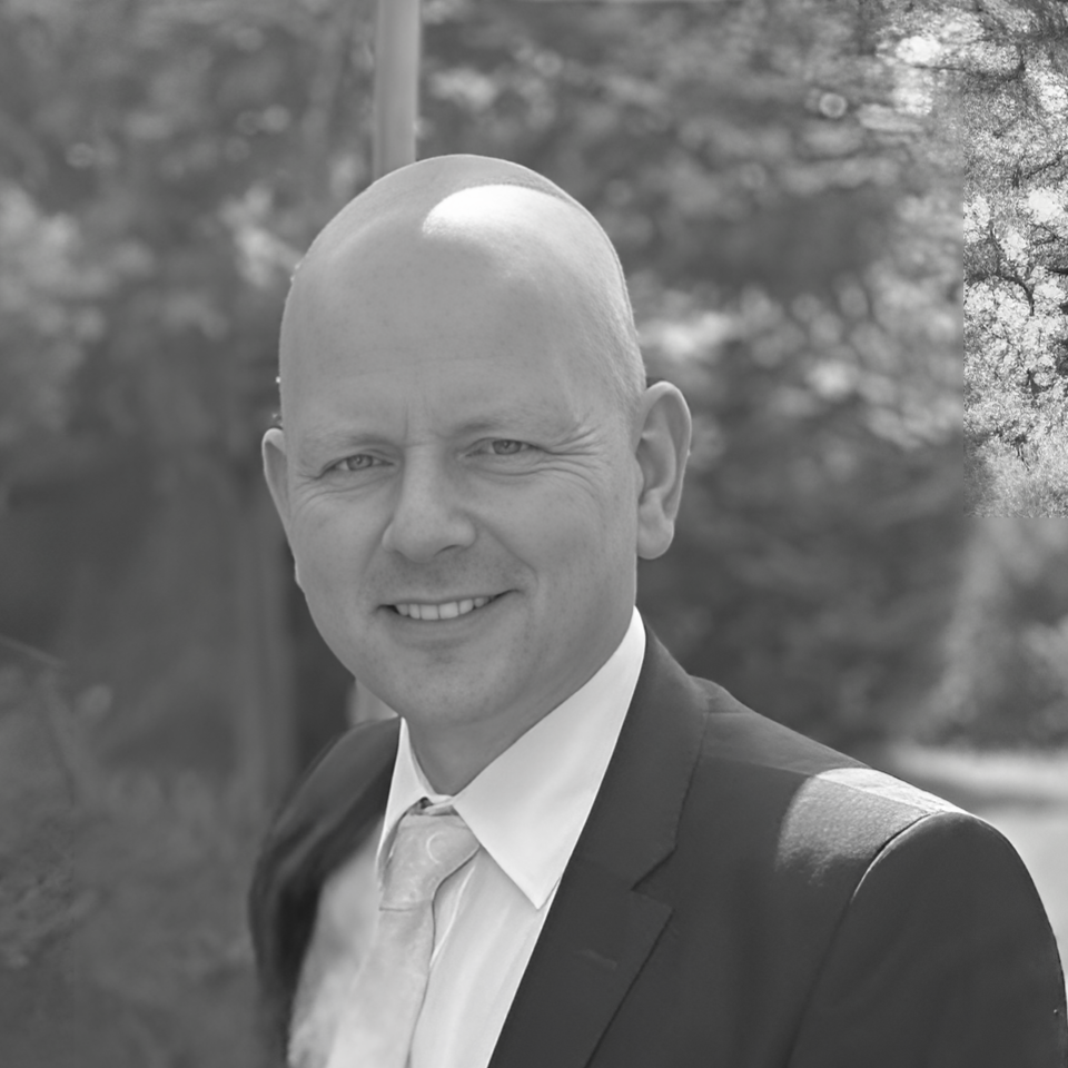 A man in a suit and tie is smiling in a black and white photo.