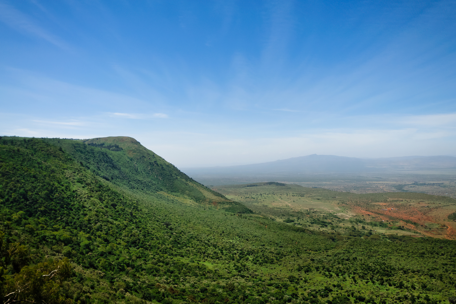 A view of a lush green valley surrounded by mountains on a sunny day.