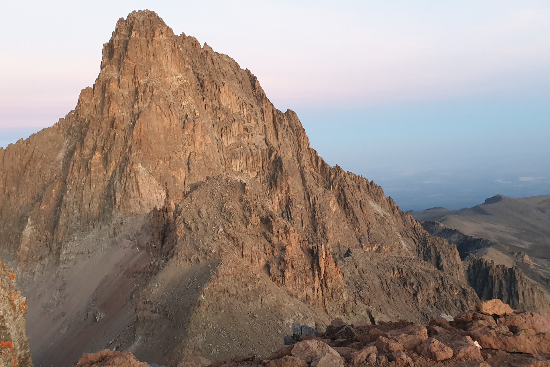 A large rocky mountain with a blue sky in the background