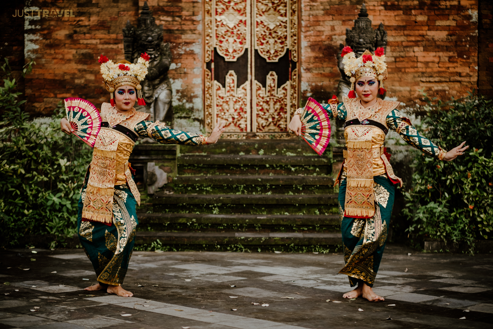 Two women in traditional costumes are dancing in front of a building.