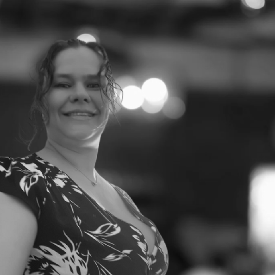 A woman in a floral dress is smiling in a black and white photo