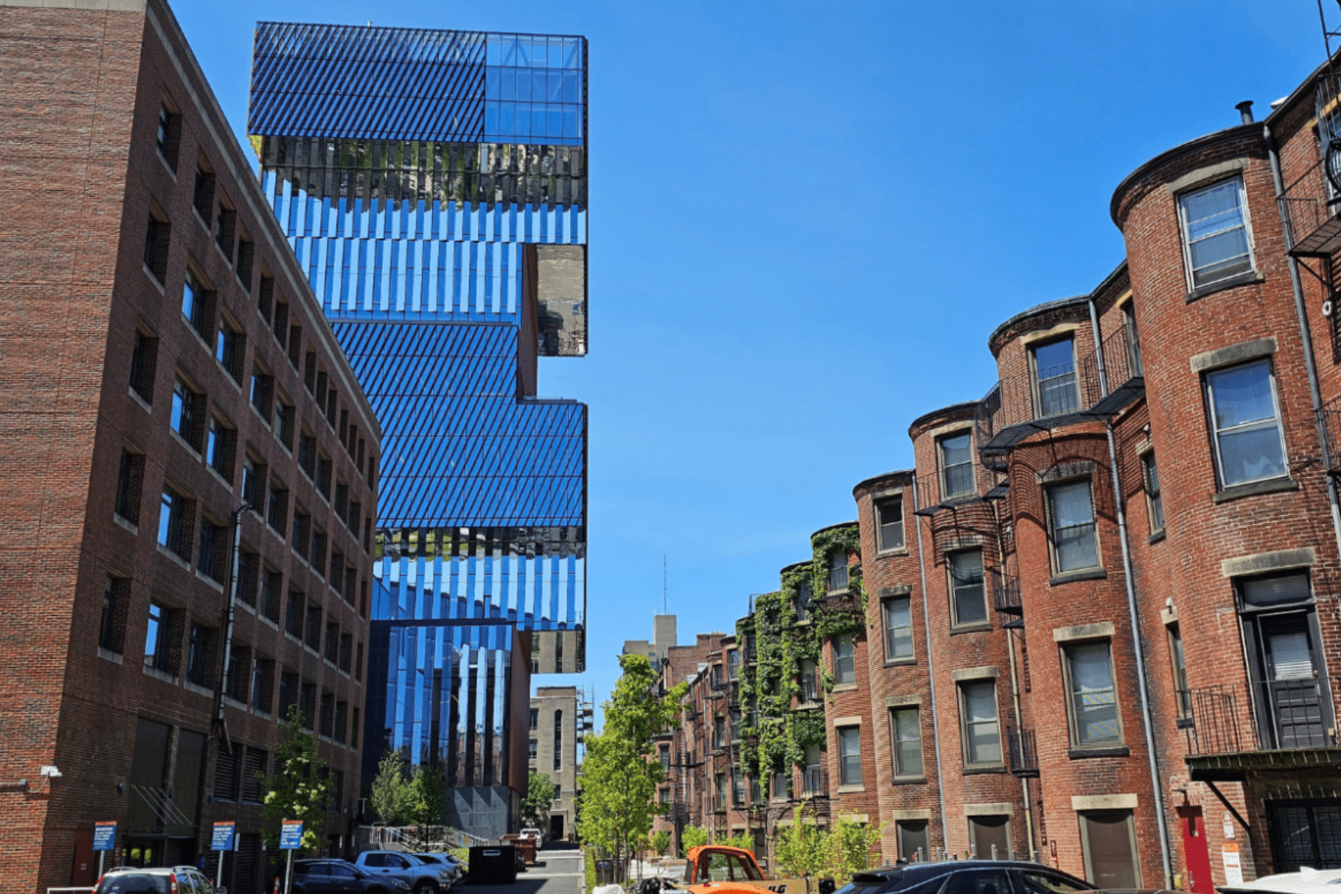 A tall building with a lot of windows is surrounded by brick buildings