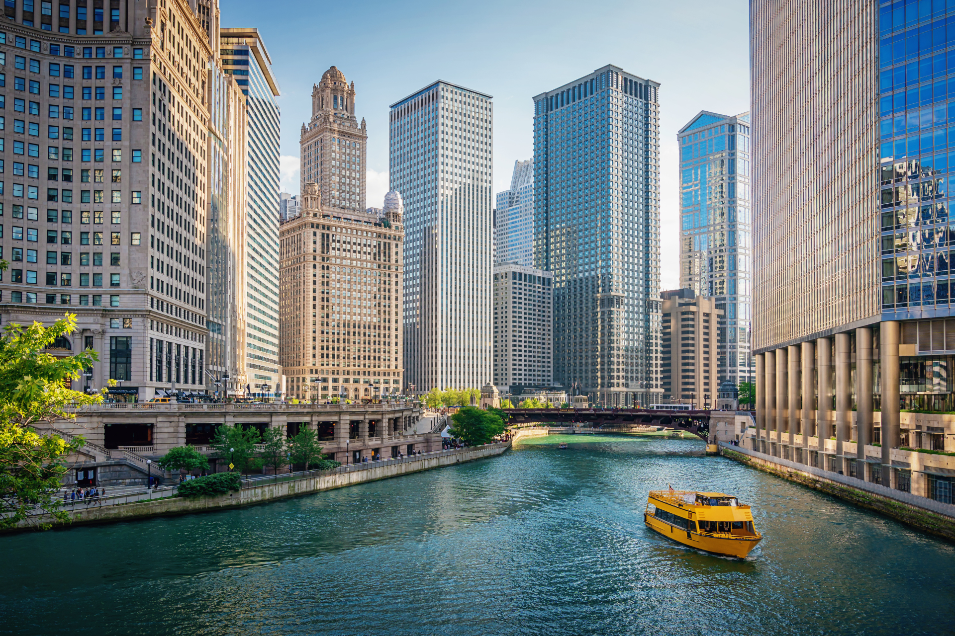 A yellow boat is floating down a river in a city.