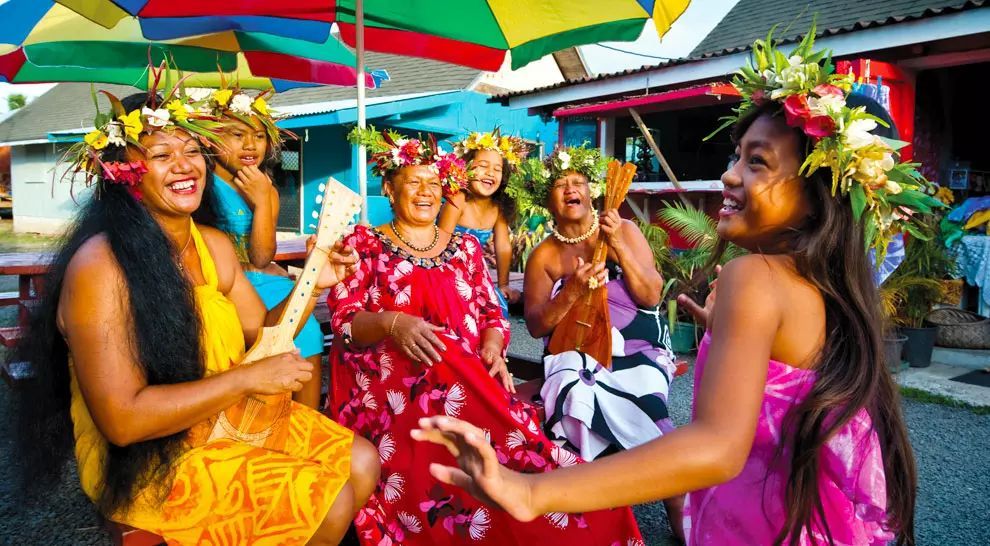 A group of women are dancing and singing under colorful umbrellas.