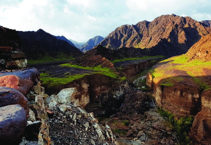 A valley with mountains in the background and rocks in the foreground