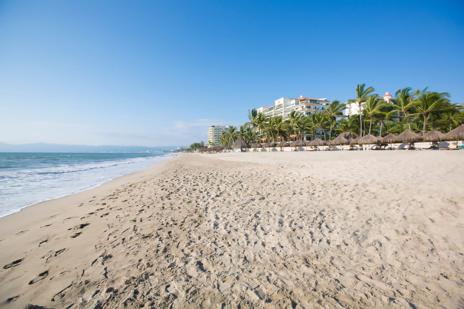 A beach with umbrellas and a building in the background