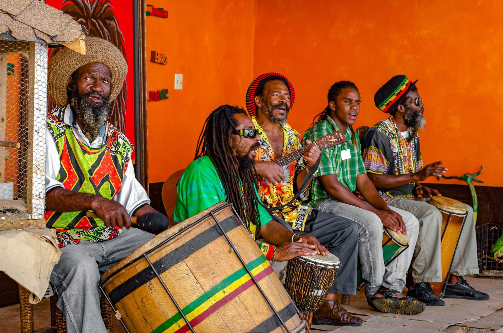 A group of men are sitting next to each other playing drums.