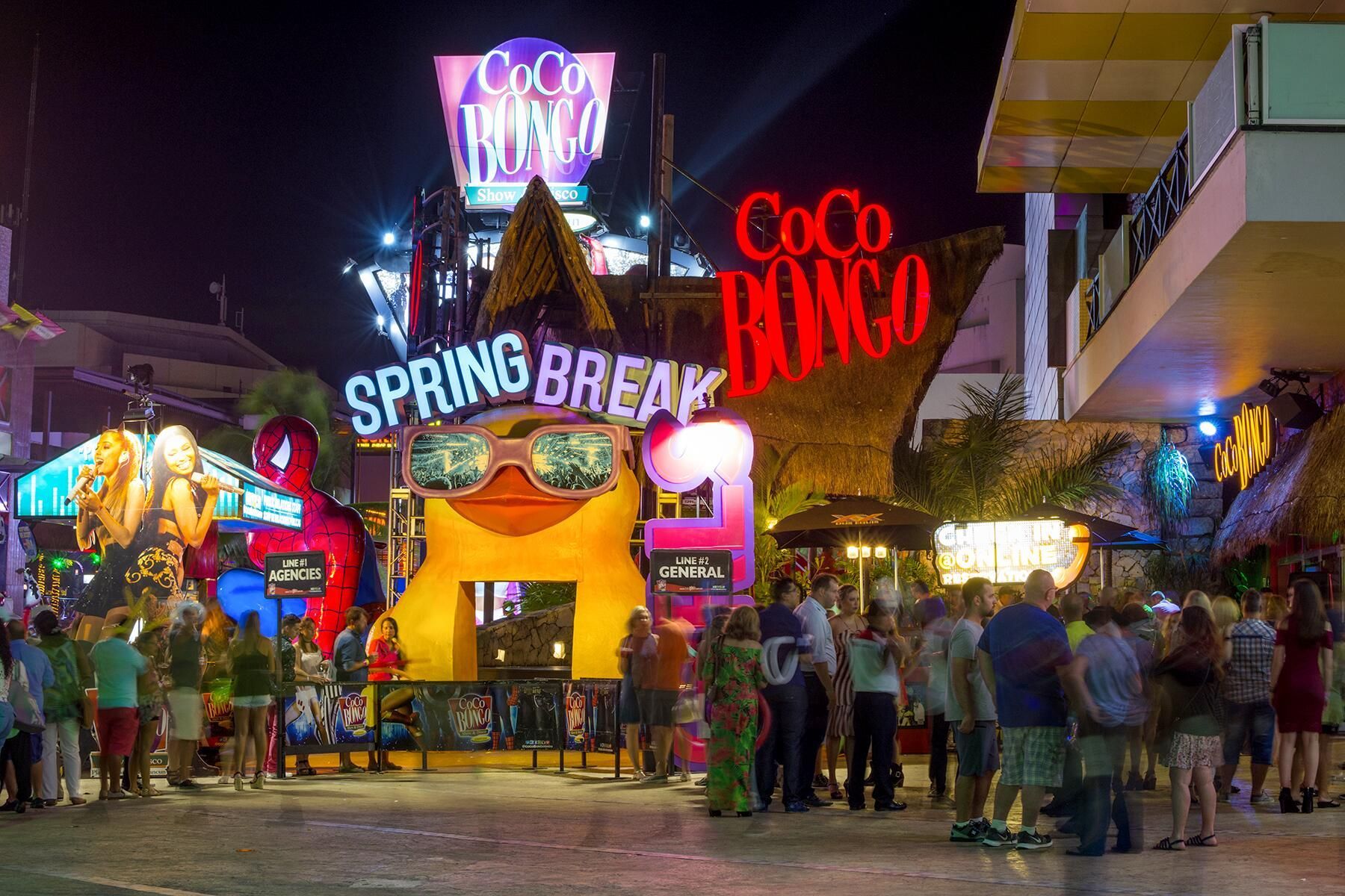 A group of people are standing in front of a building that says spring break.