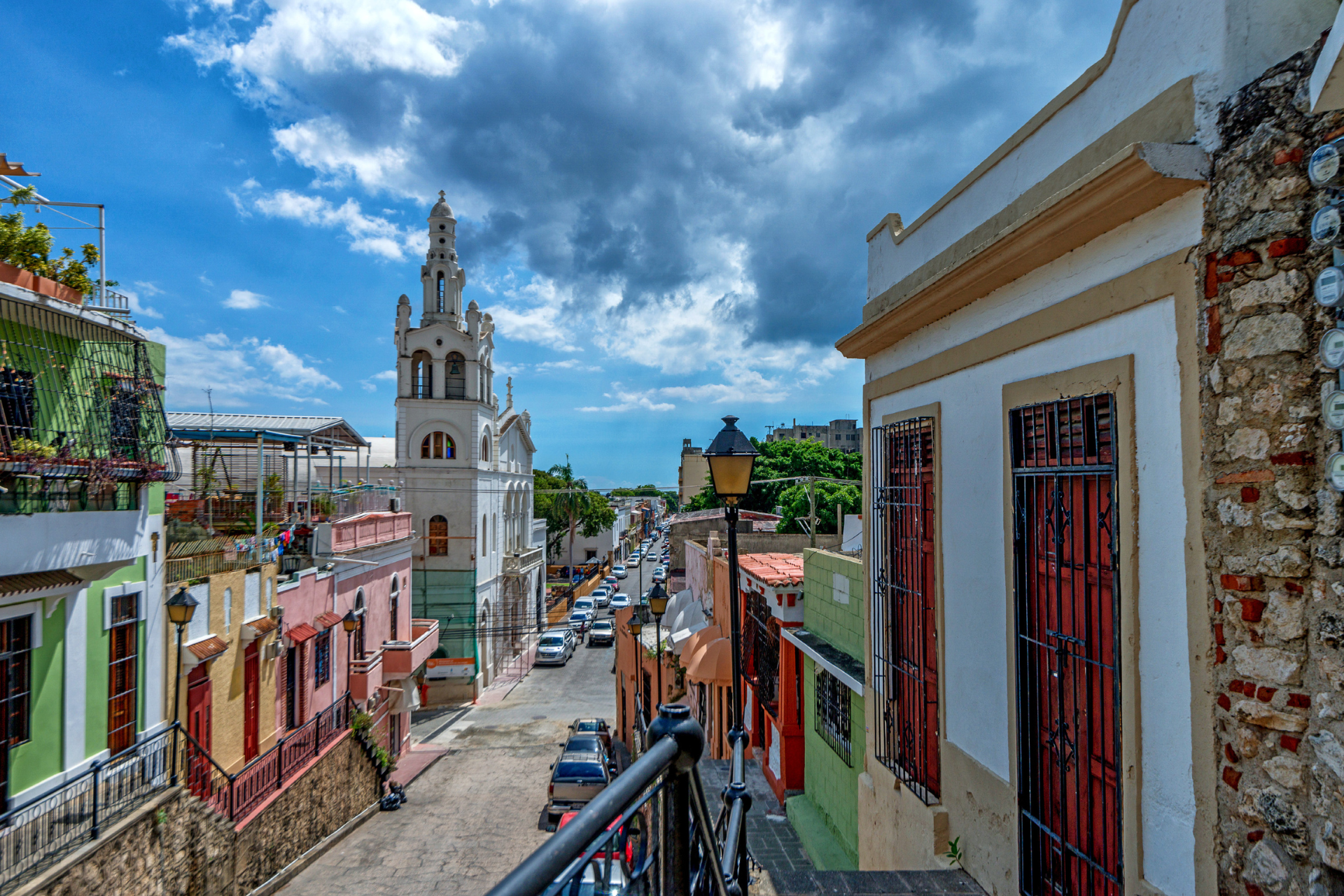 A view of a city street from a balcony with a clock tower in the background.