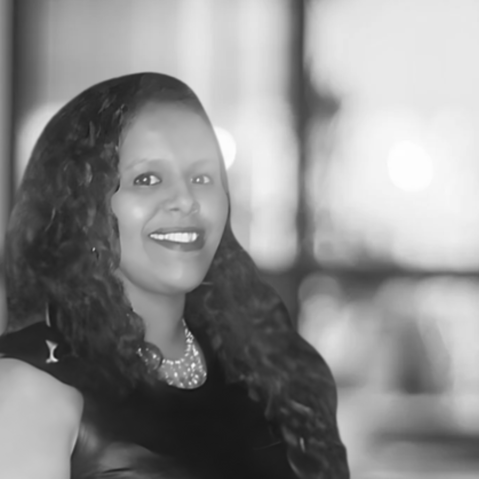 A woman with long hair is smiling in a black and white photo.