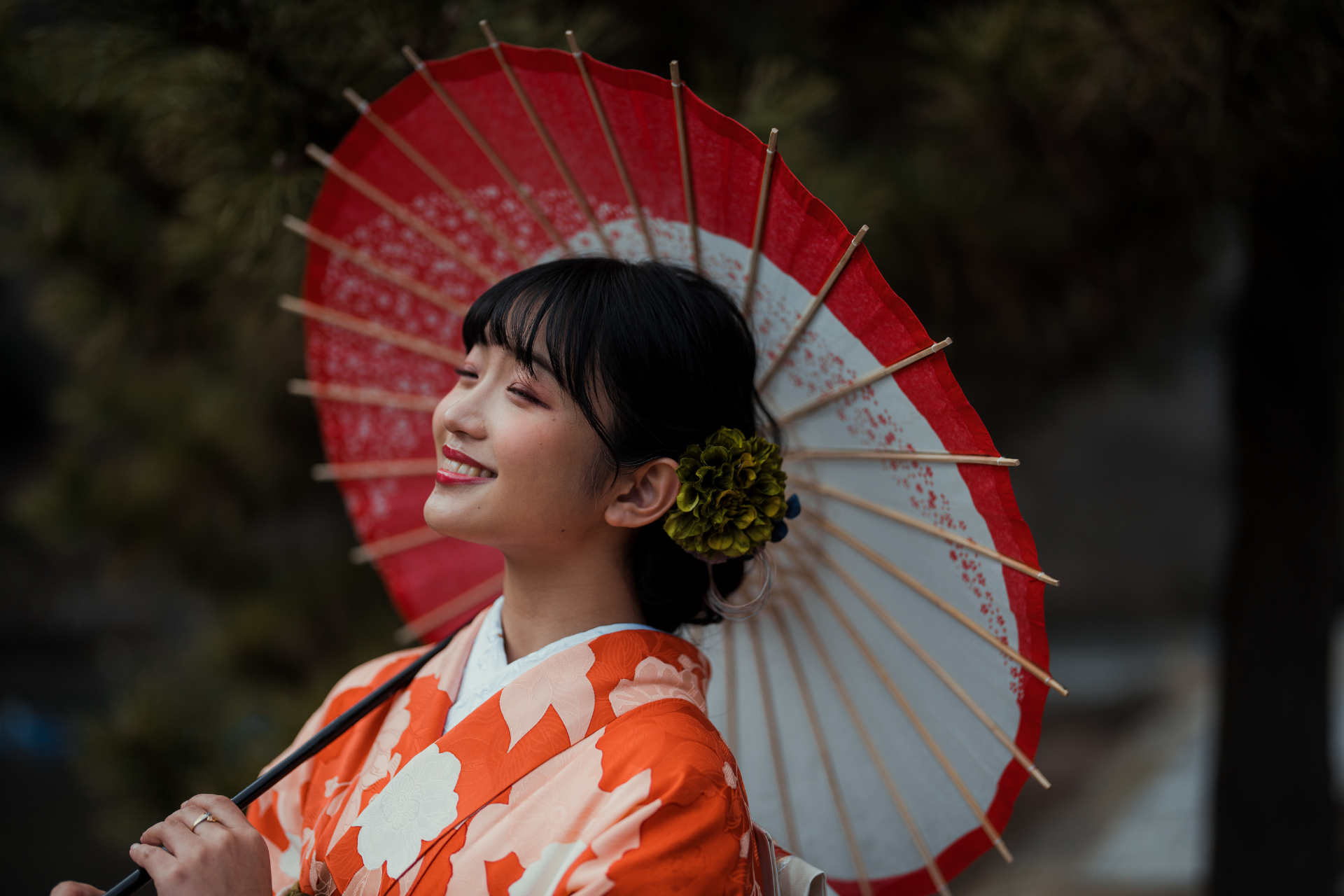 A woman in a kimono is holding a red and white umbrella.