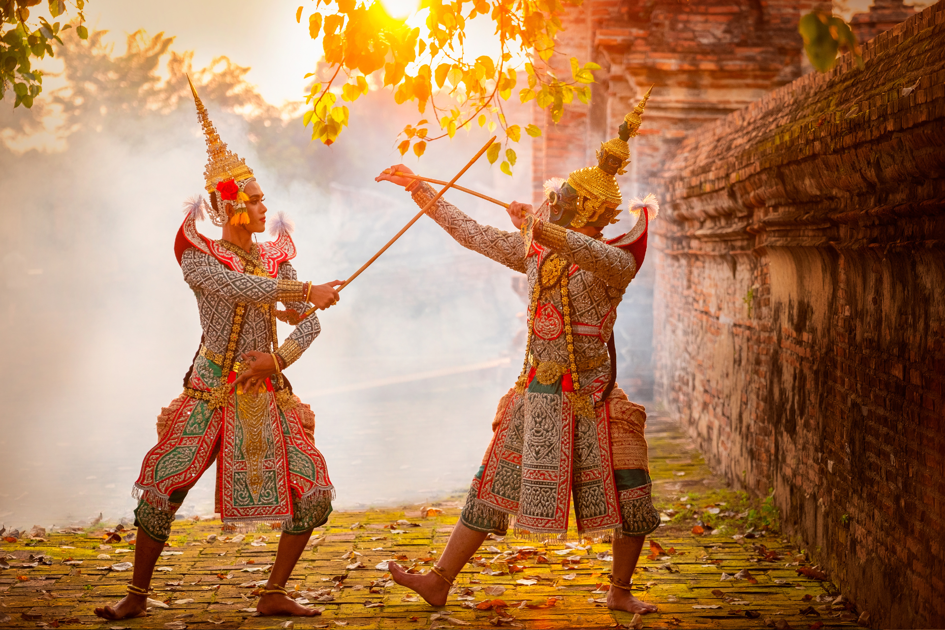 Two men in traditional costumes are standing next to each other holding sticks.