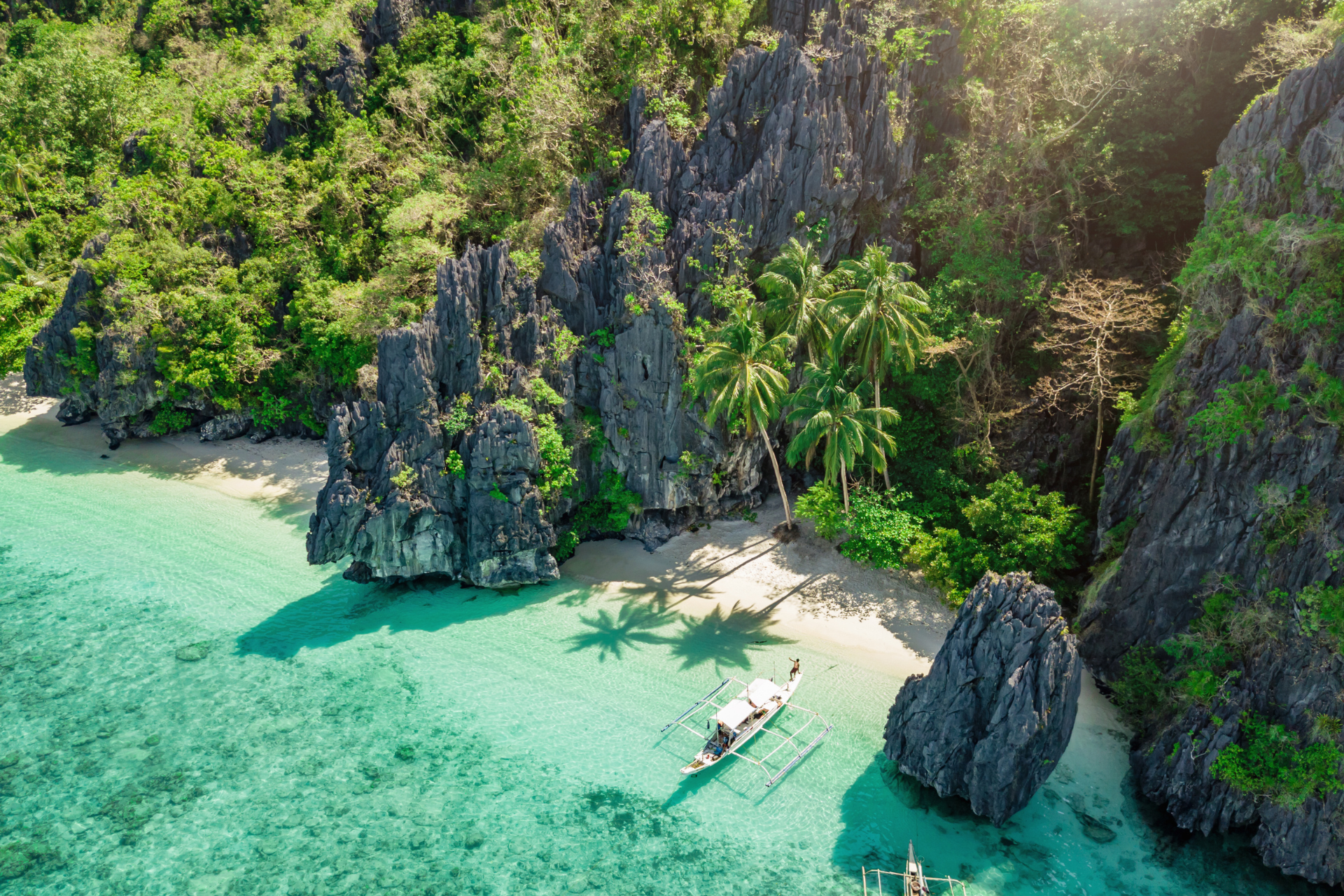 An aerial view of a tropical island with a boat in the water.