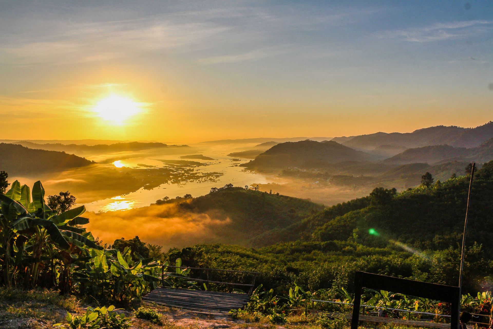 A sunset over a river surrounded by mountains and trees