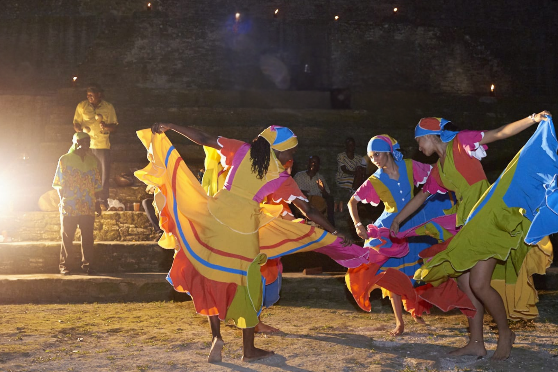 A group of people in colorful dresses are dancing on a stage