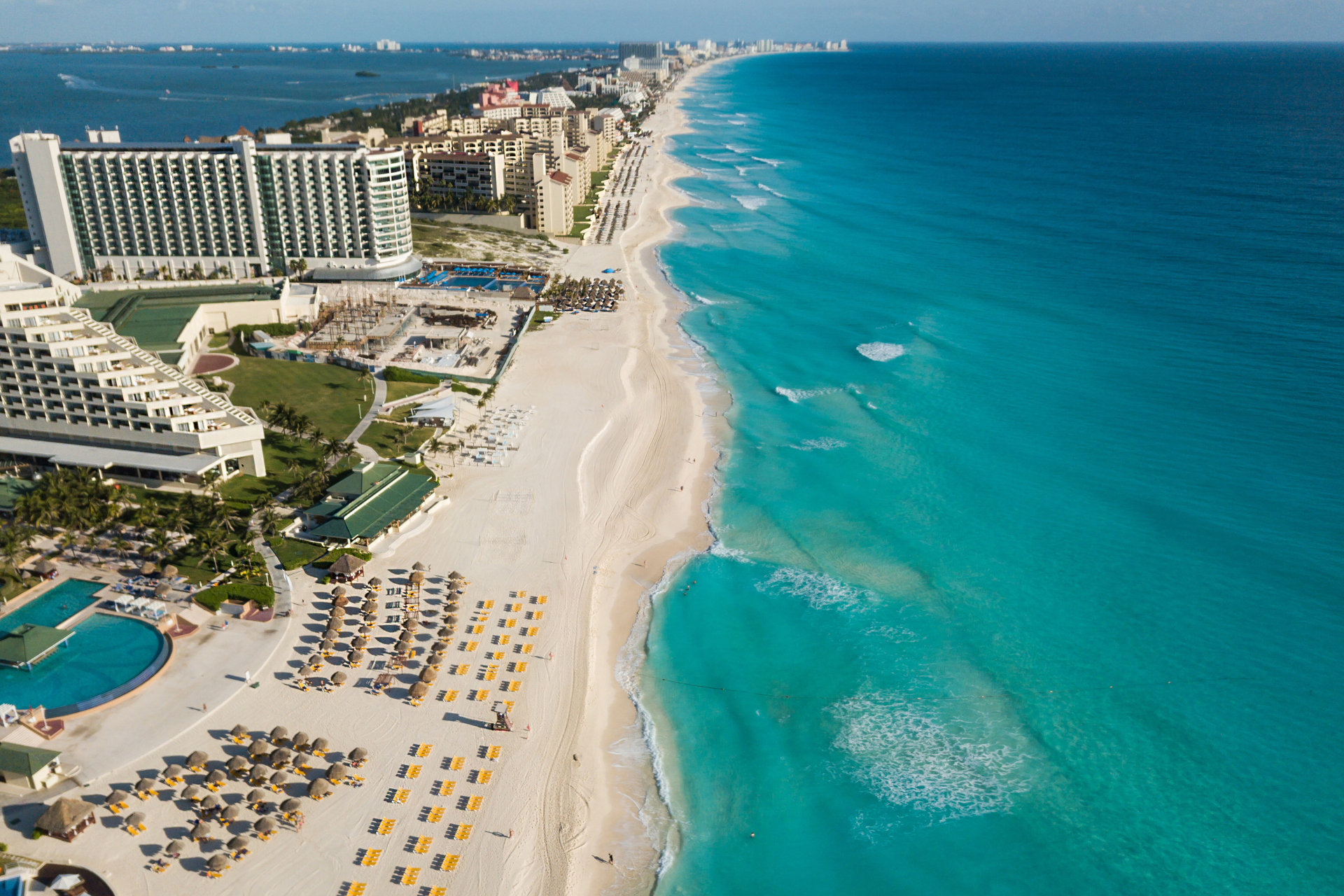 An aerial view of a beach with a hotel in the background.