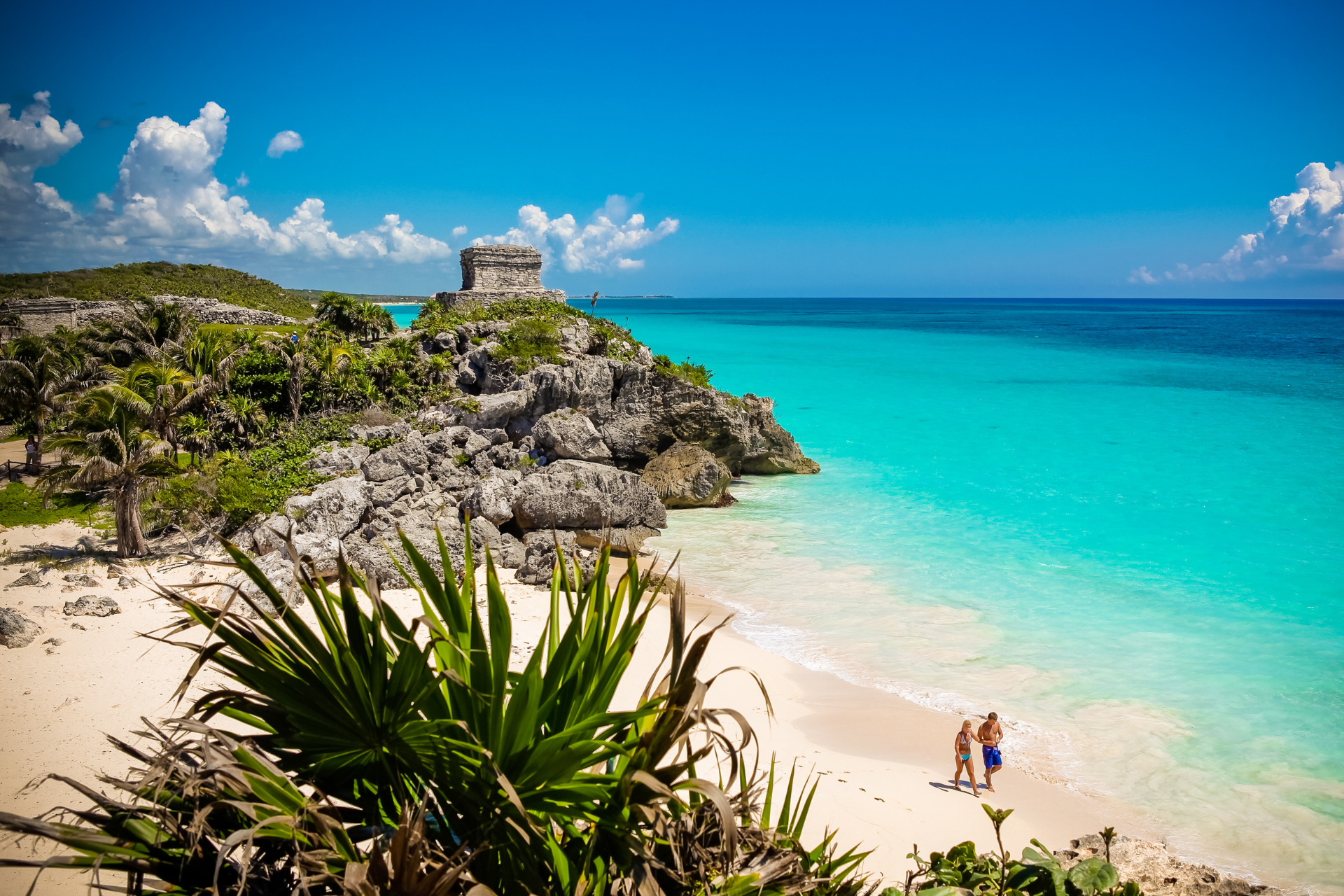 A couple is standing on a beach next to the ocean.