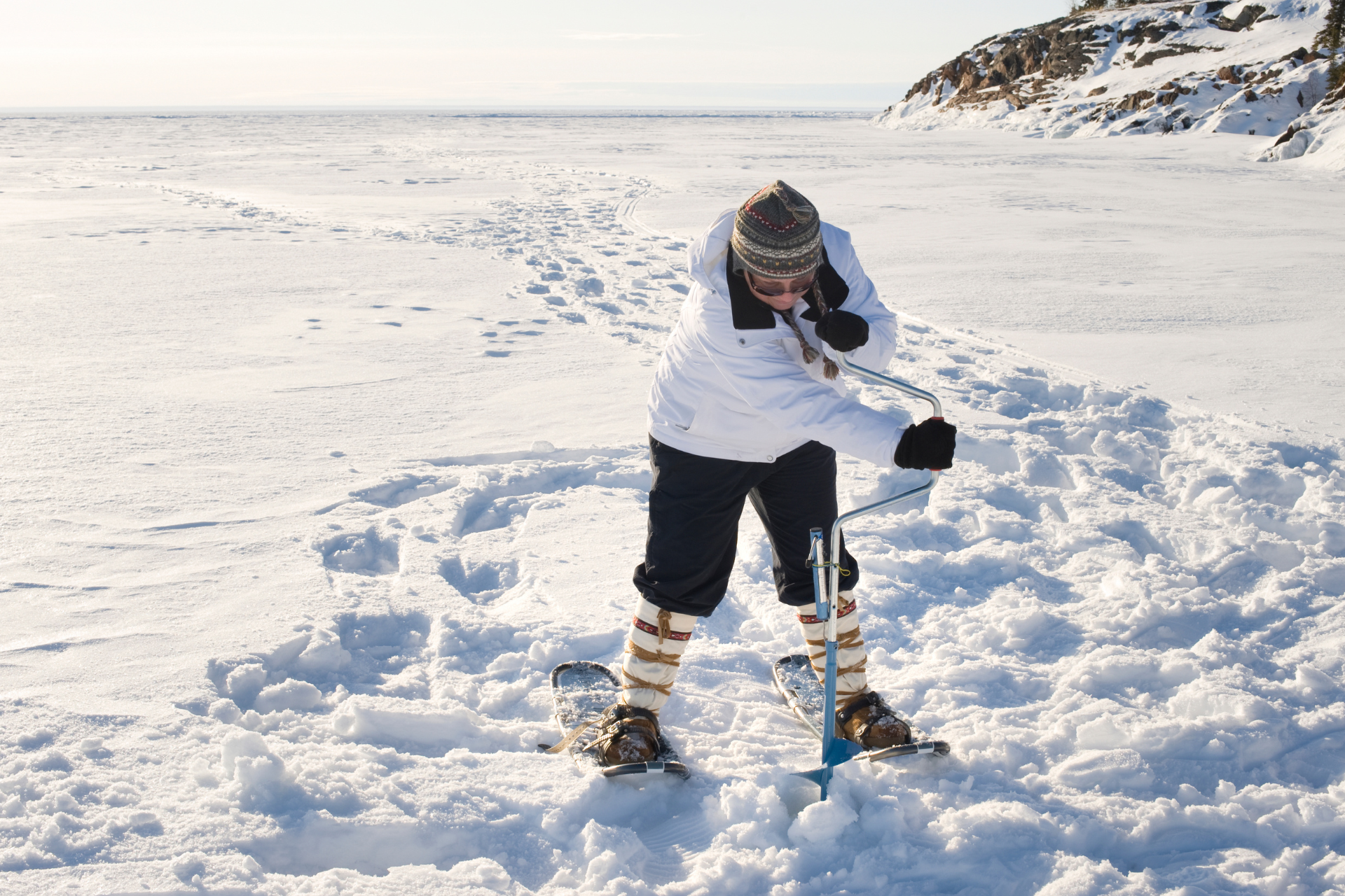 A person is standing in the snow using a shovel