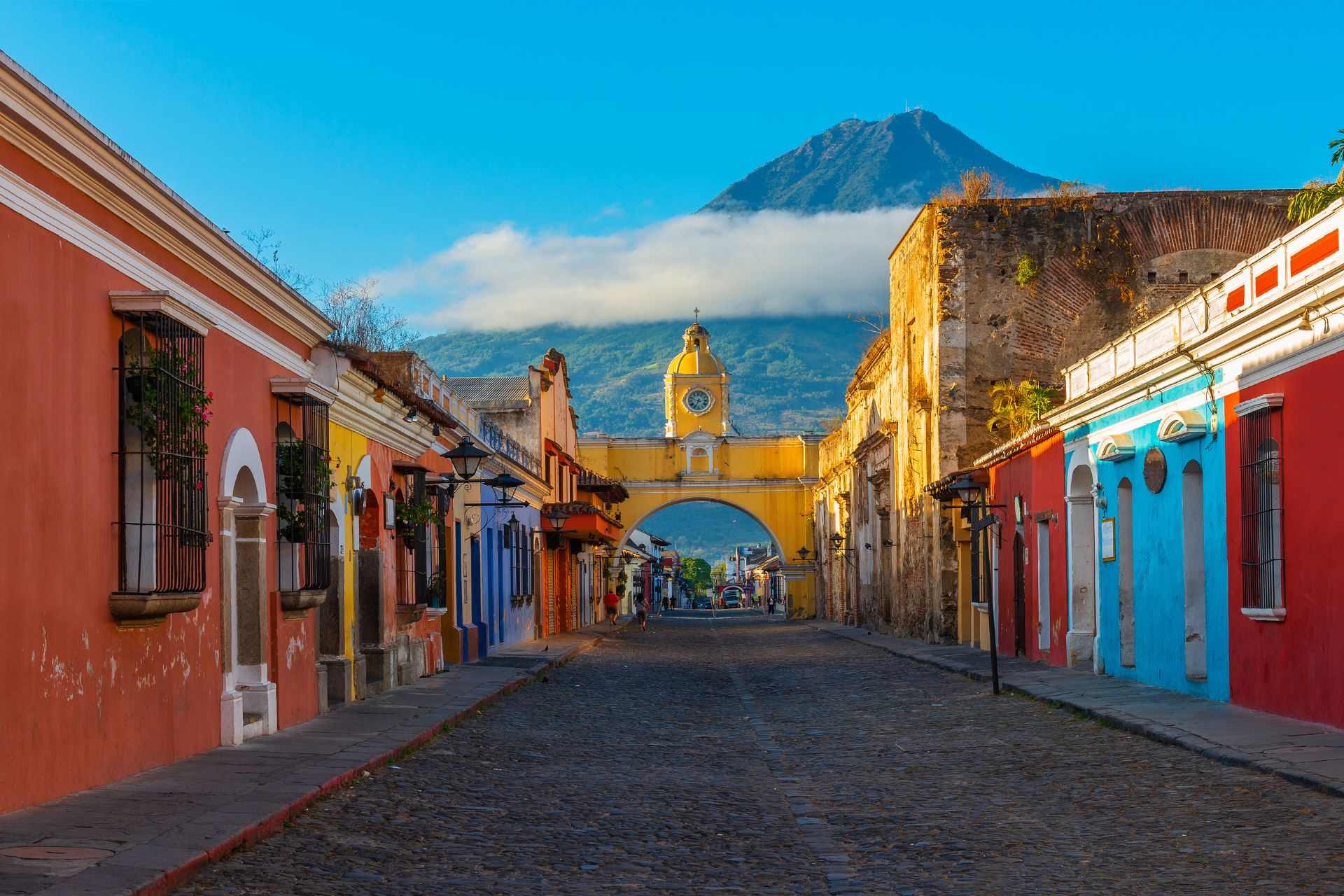 A row of colorful buildings on a cobblestone street with a mountain in the background.